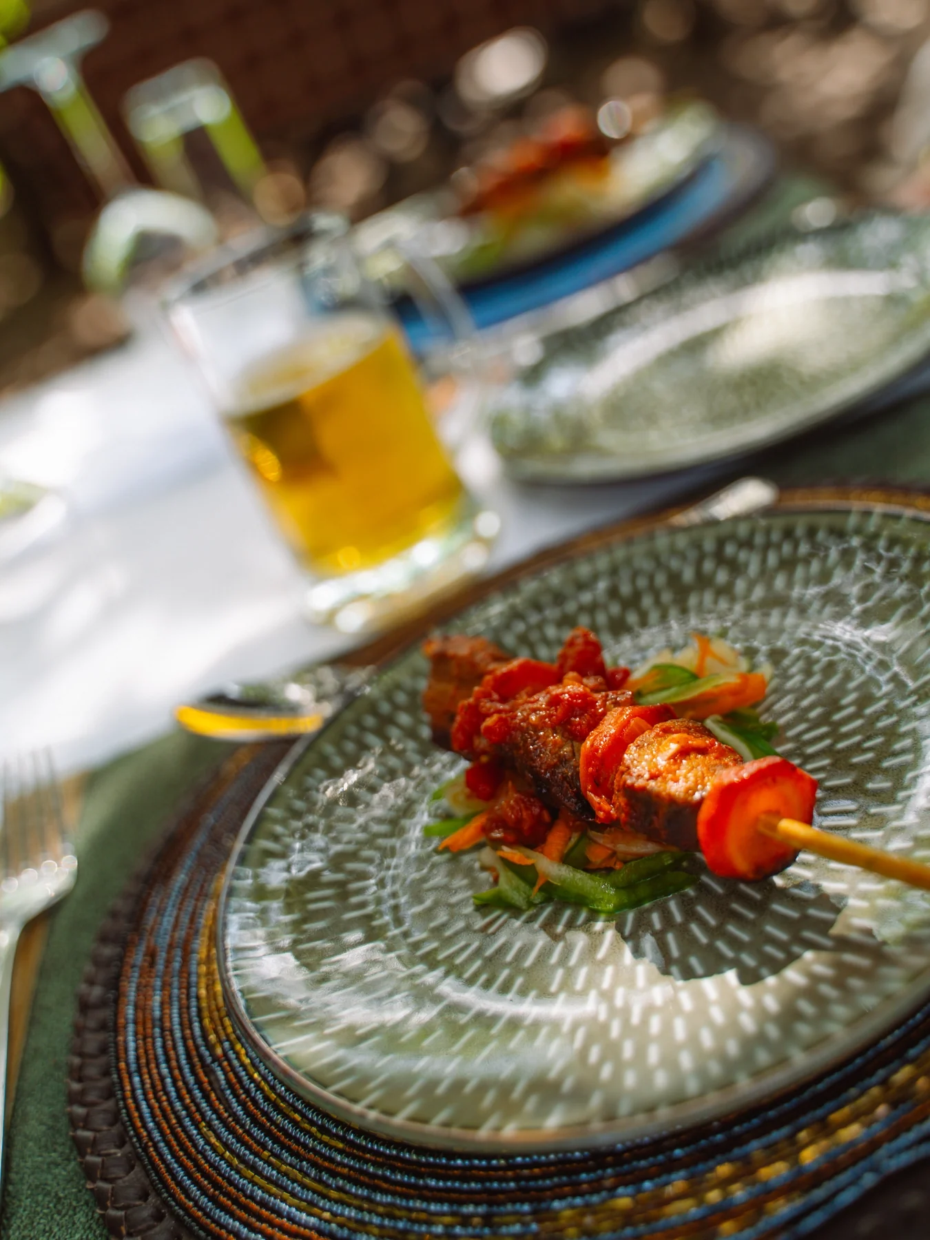 Skewers and a drink on a woven table setting