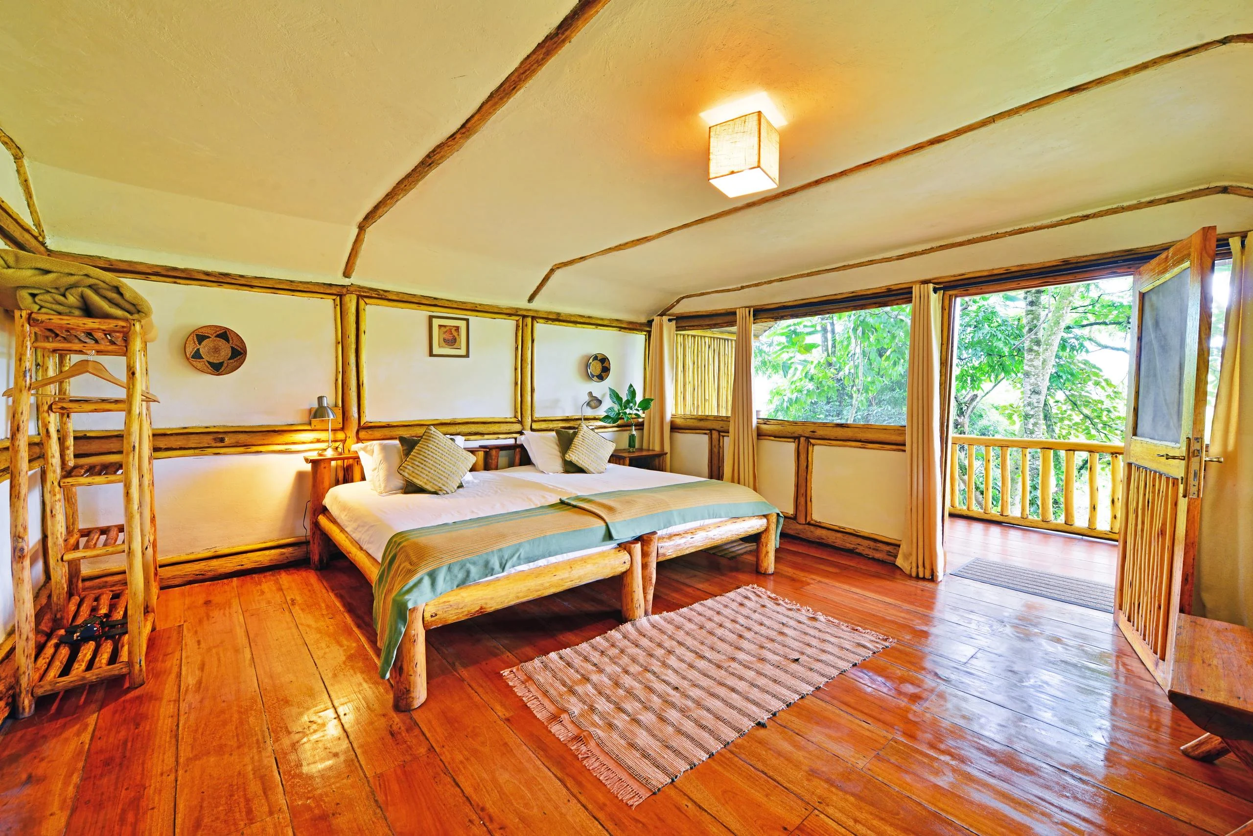 A cottage bedroom with timber walls and a window onto the forest