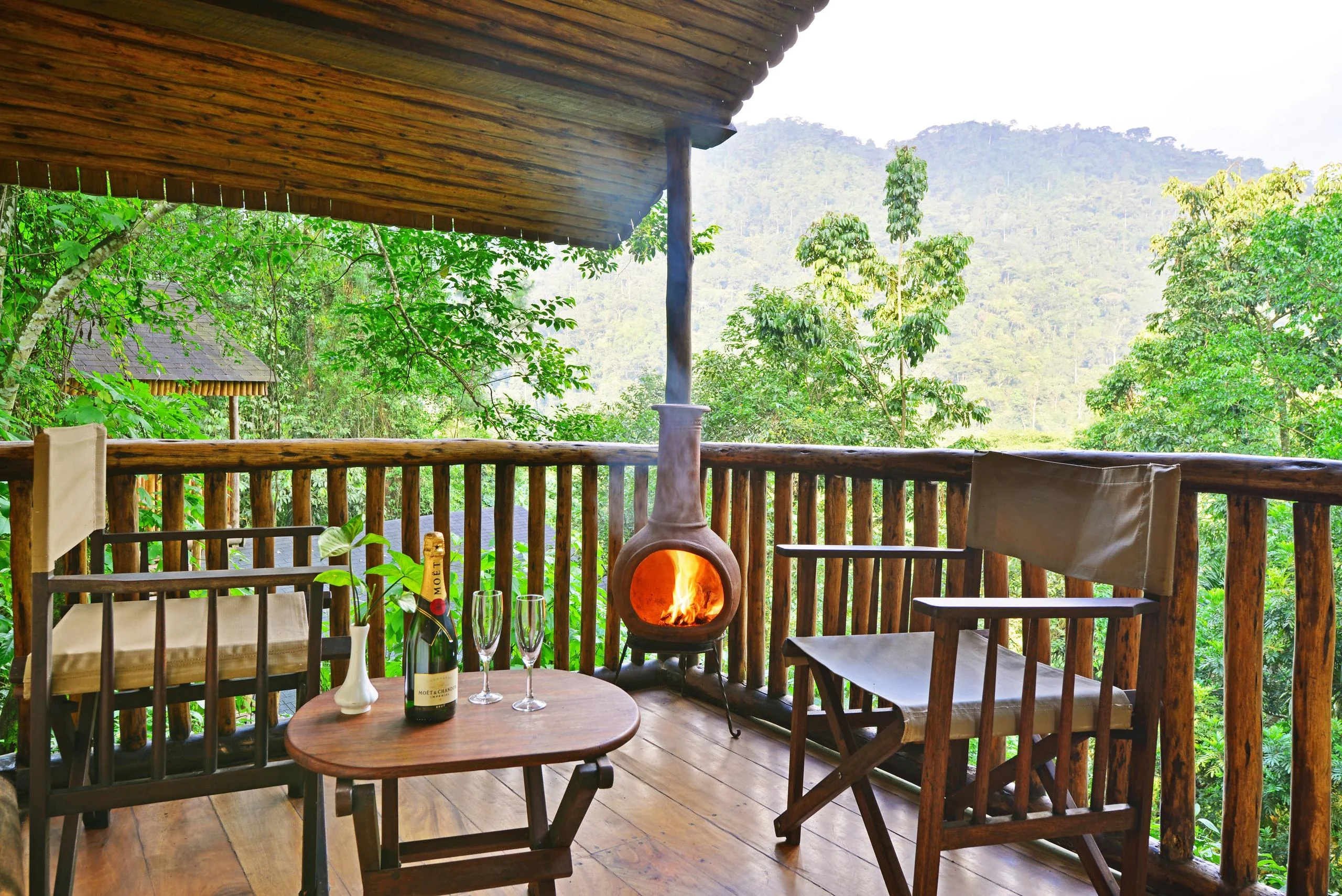 A cottage veranda with a fireplace, looking into the forest