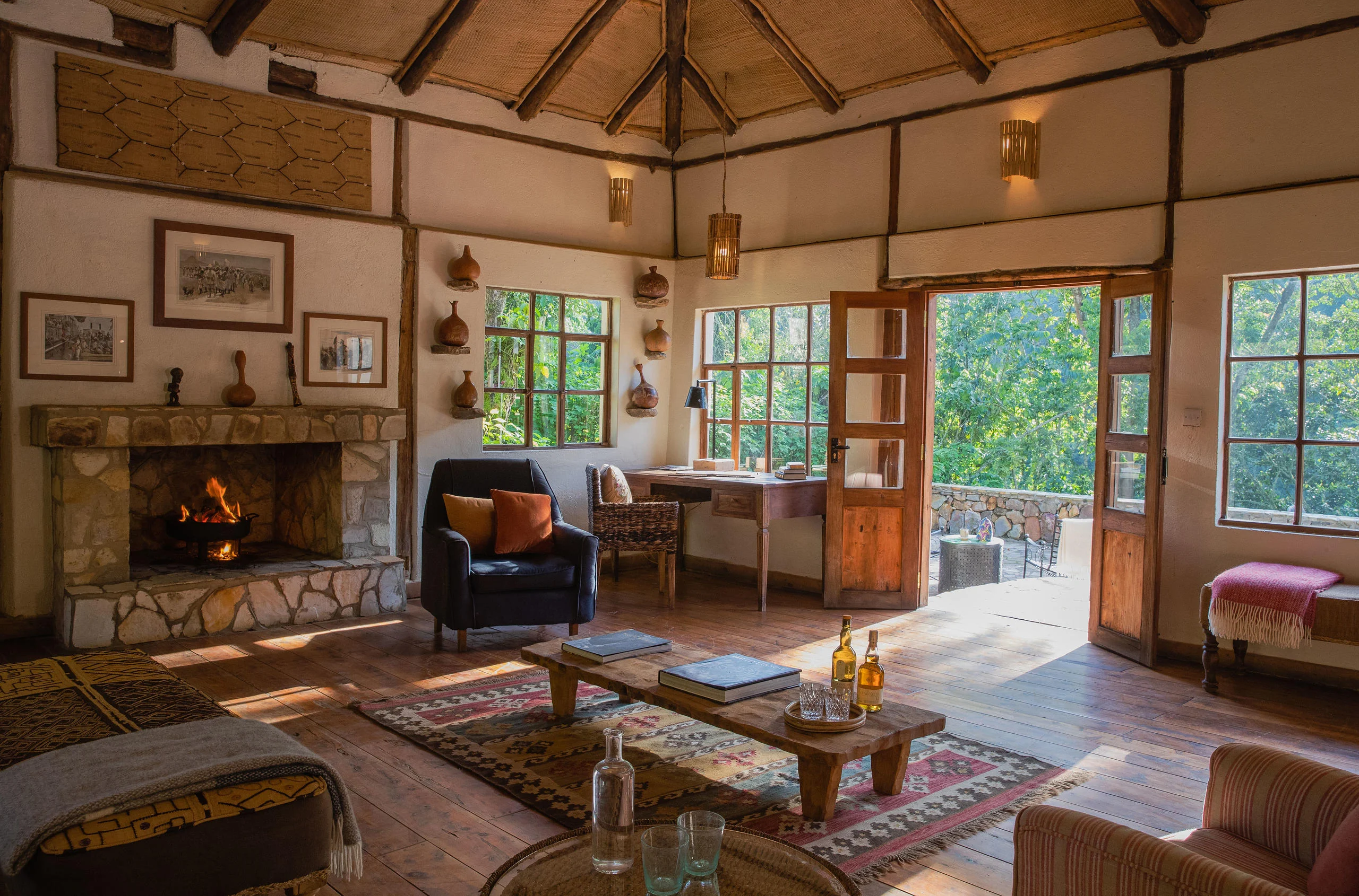 The lounge with a fireplace and windows onto the forest
