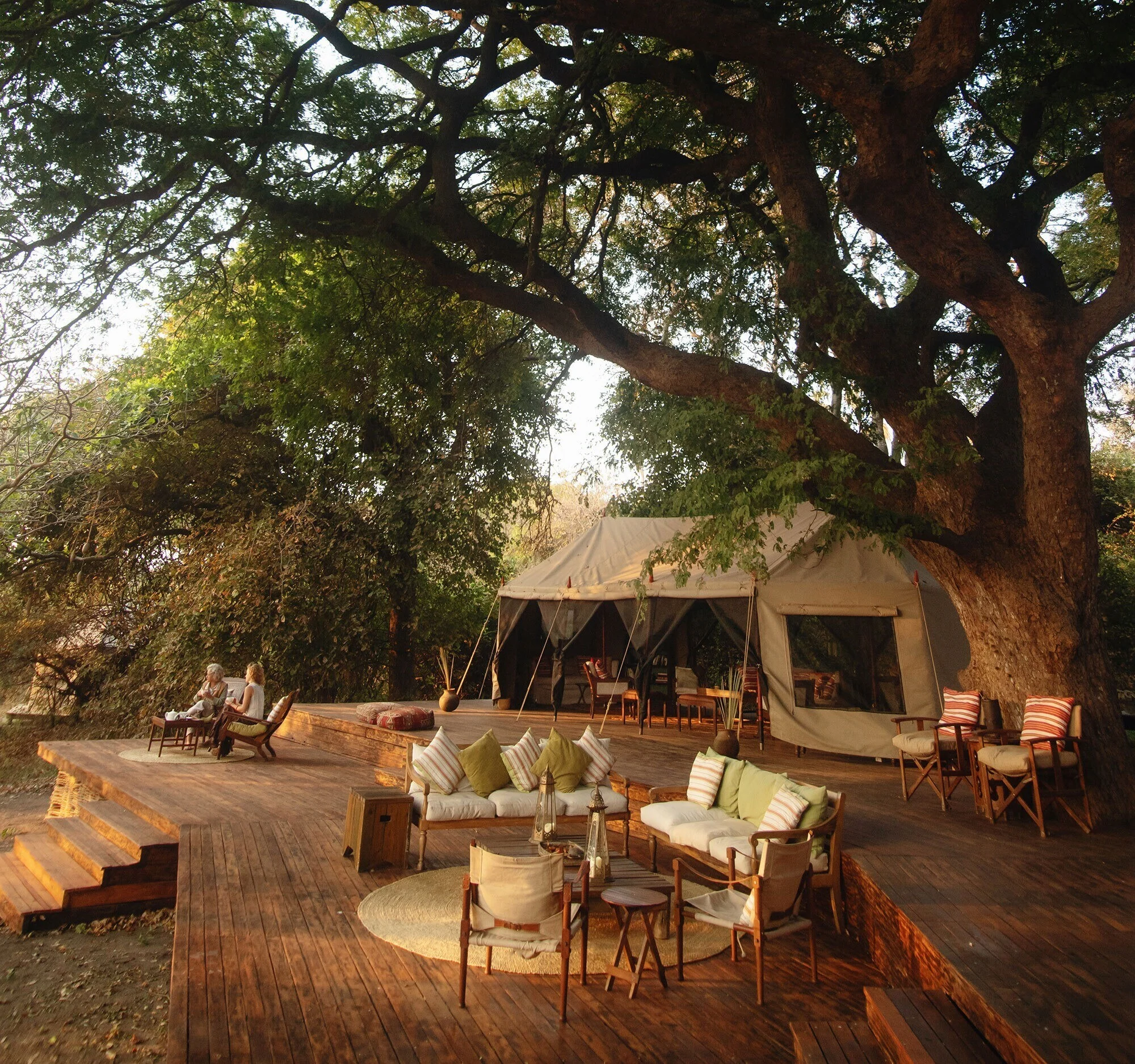 A tent deck with chairs under the trees