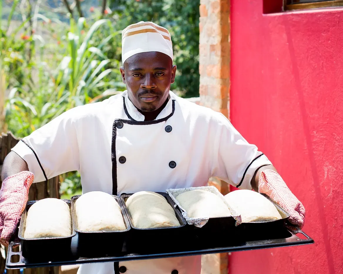 A chef carrying a tray of bread rolls