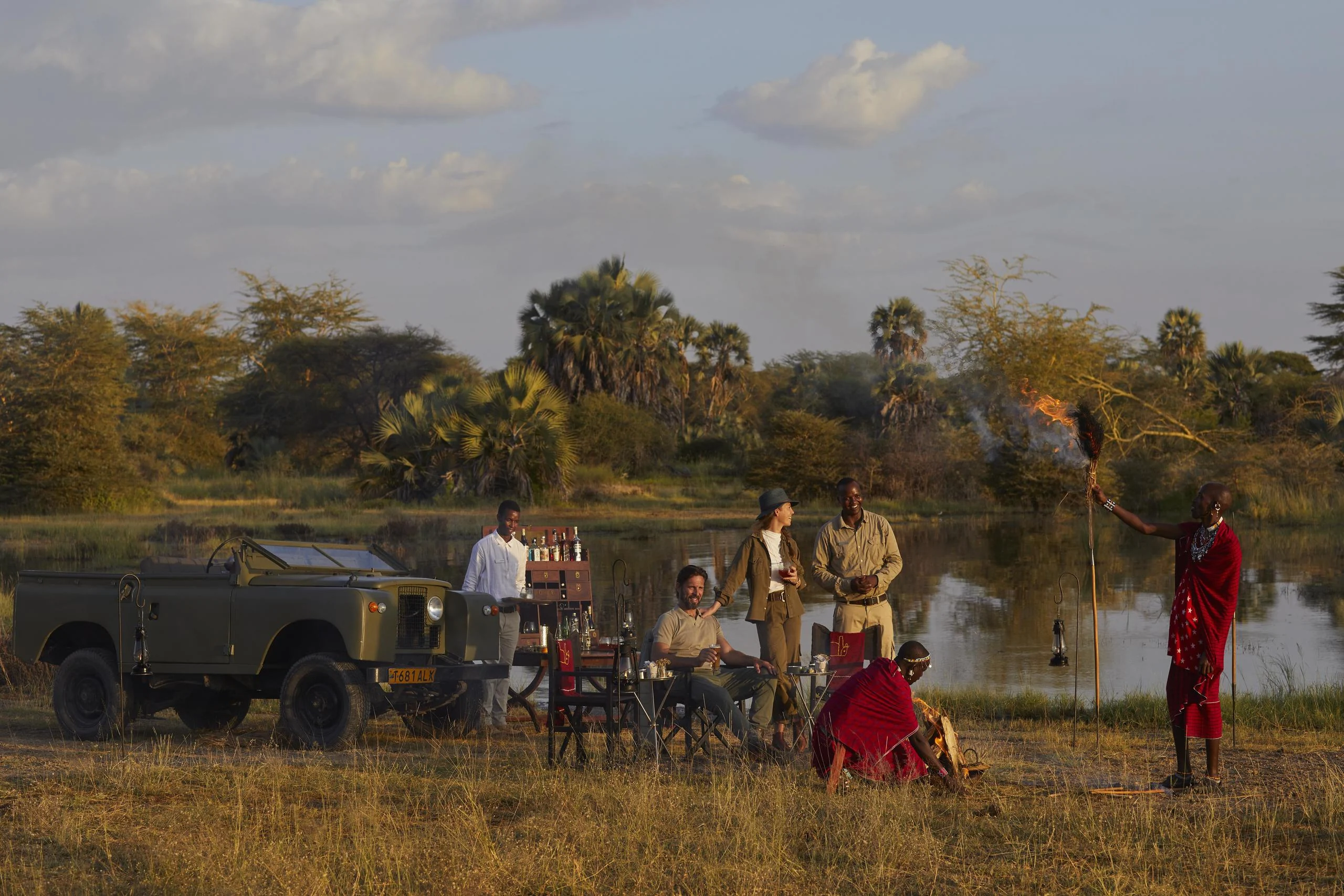 Guests and guides beside a safari vehicle at the lakeshore