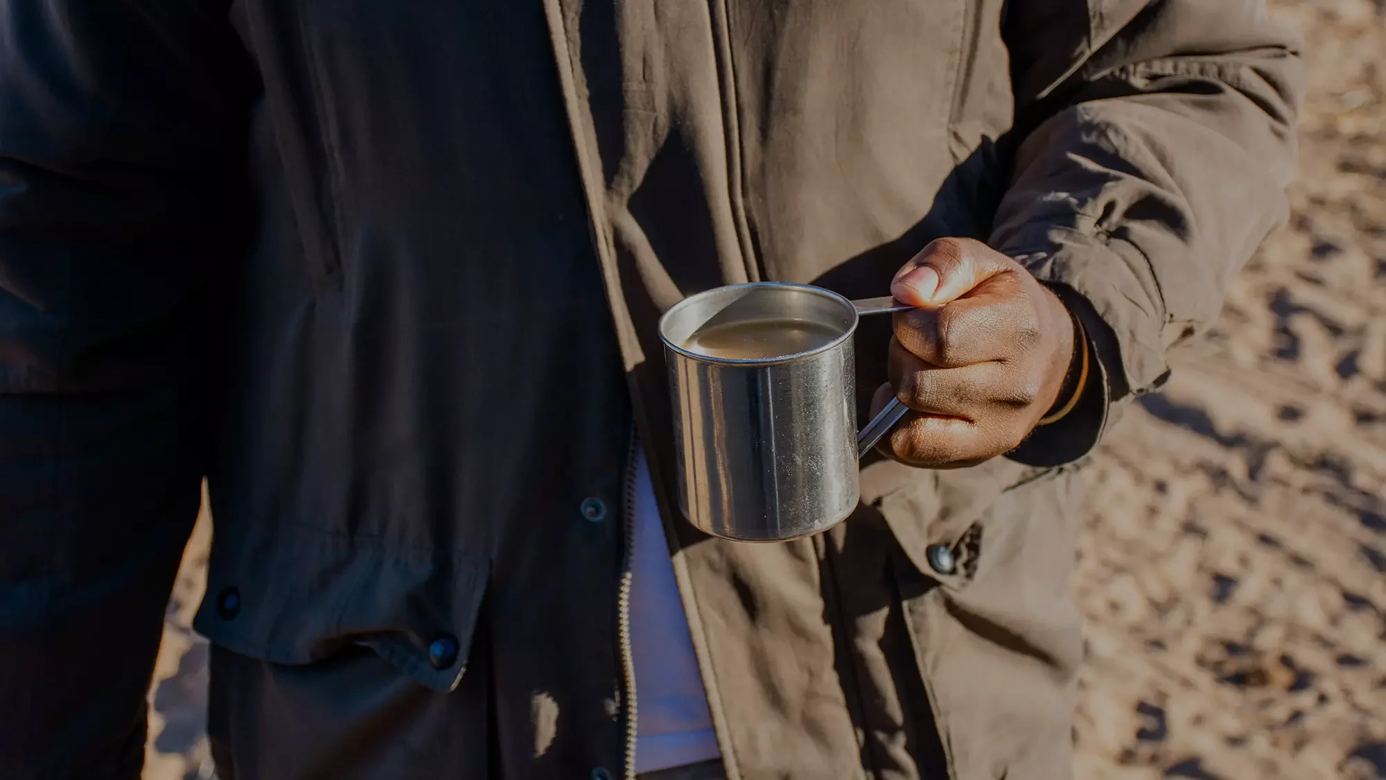 A cup of coffee held by a member of staff