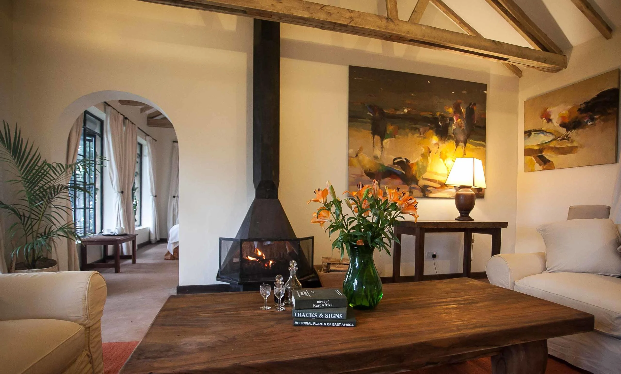 A cottage sitting room with a fireplace and paintings