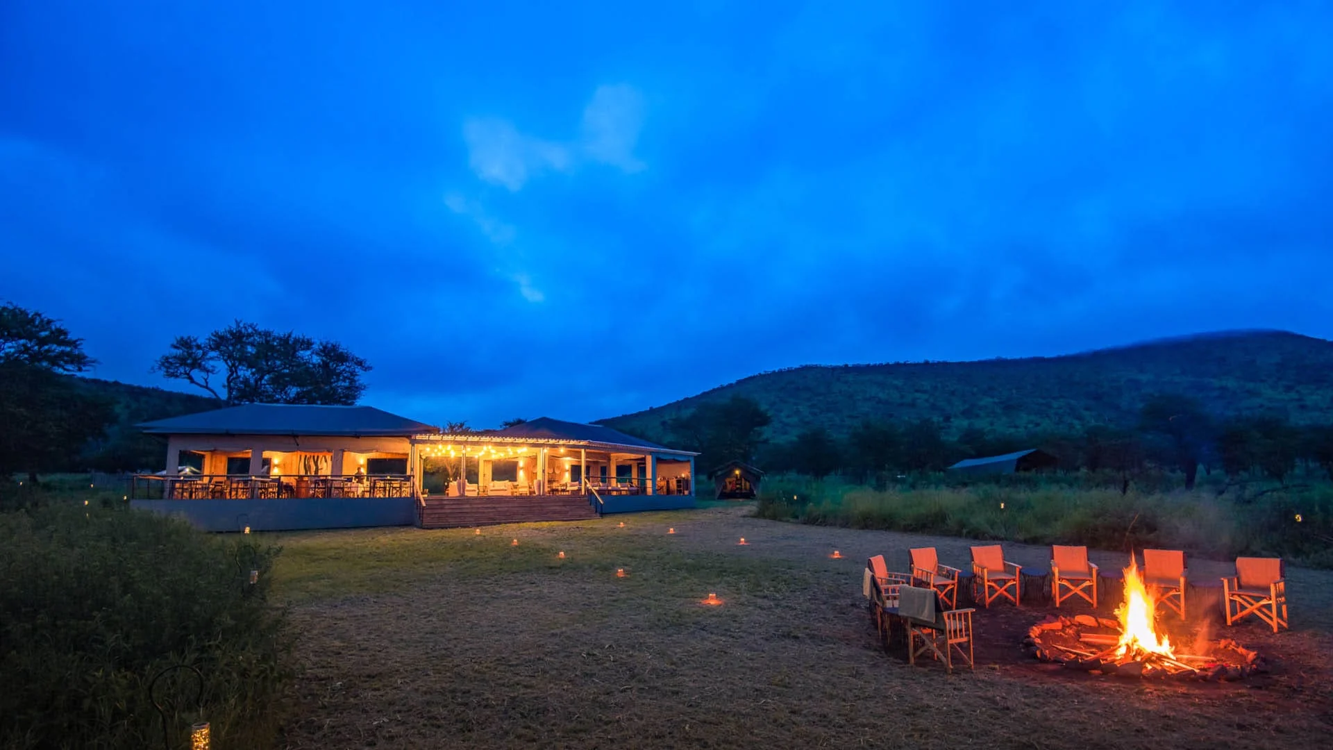 The camp at dusk with a fire lit in front of the main tent