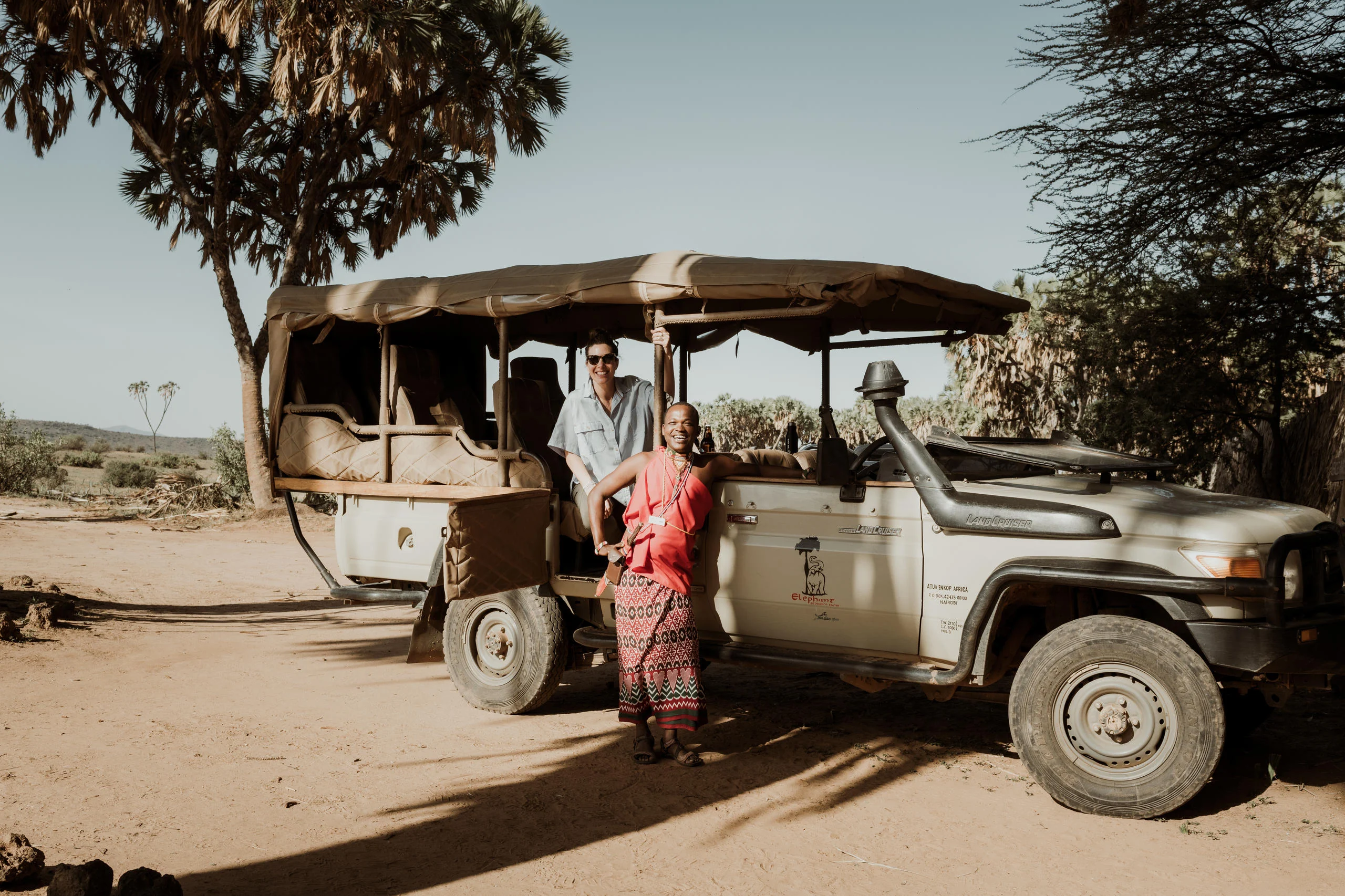 A safari vehicle beneath the trees with a member of staff