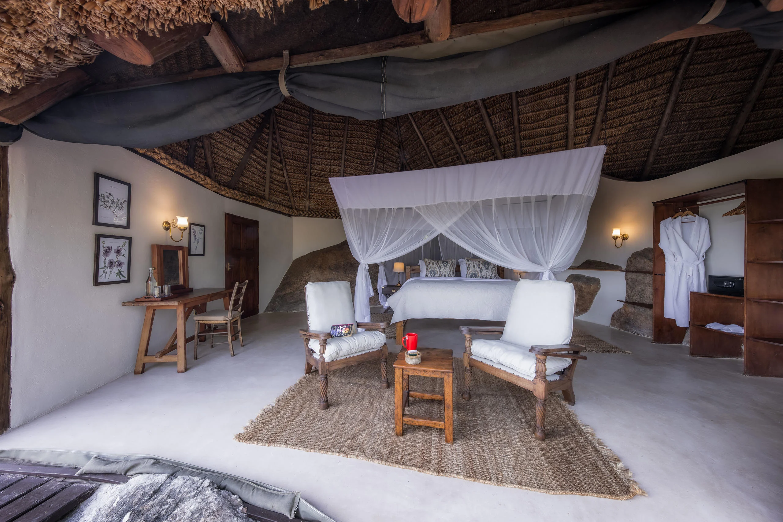 A bedroom with a draped bed and armchairs
