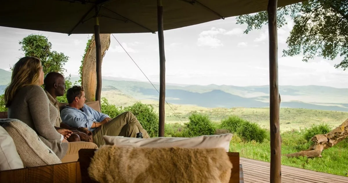 Guests on a sofa looking out from the deck over the crater rim forest