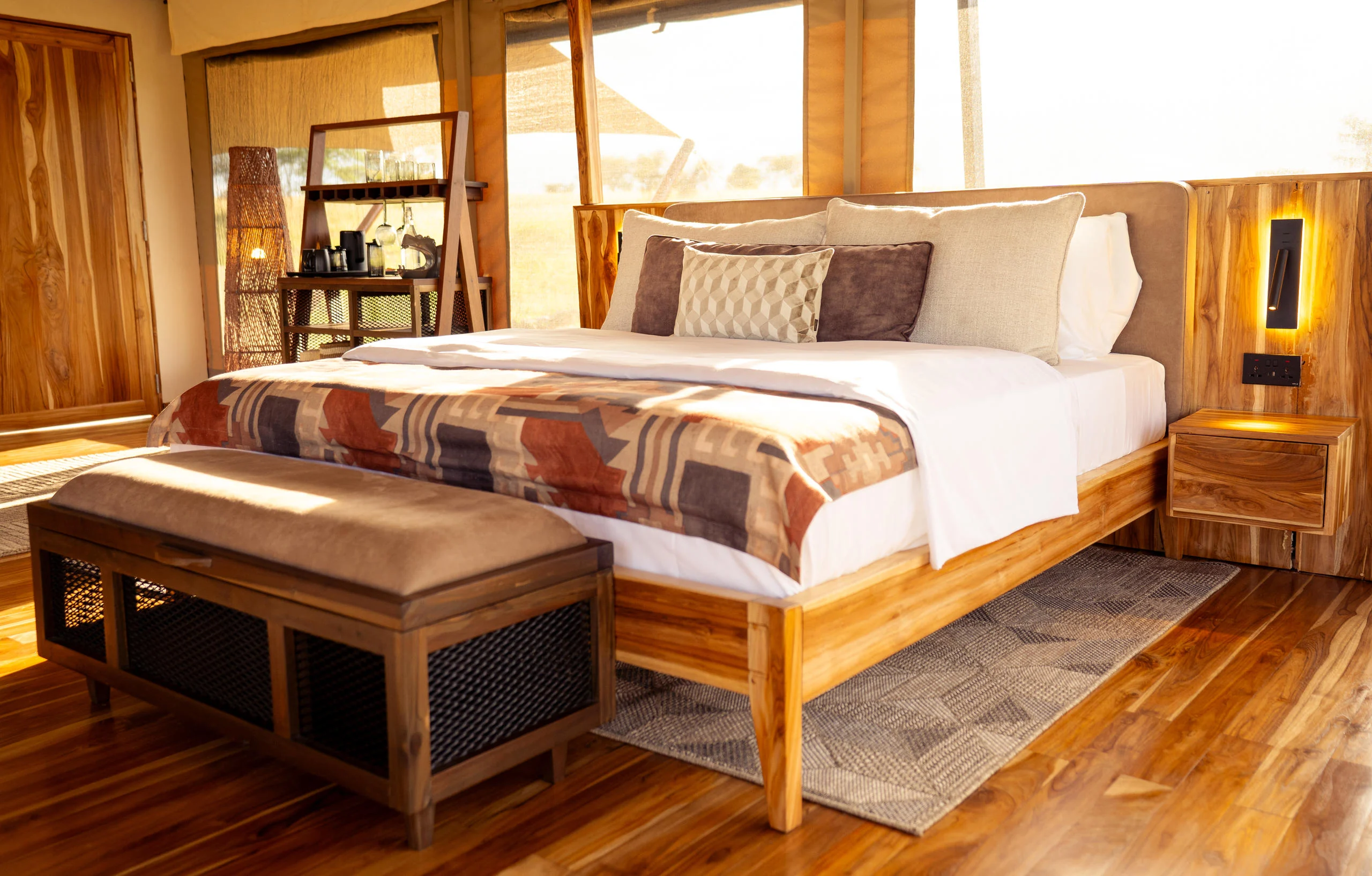 A tent bedroom with a timber bed and bench