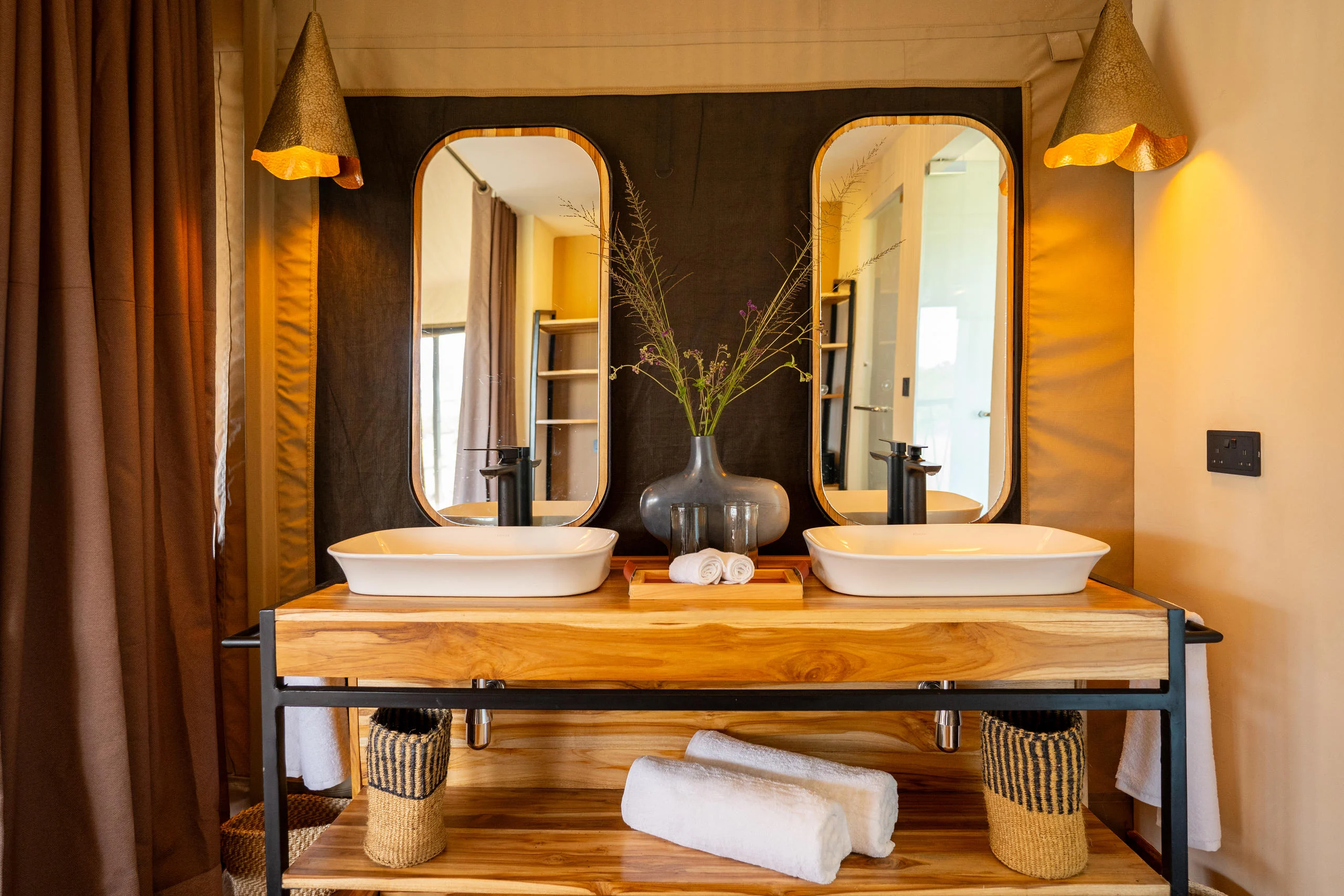 A tent bathroom with twin basins and mirrors