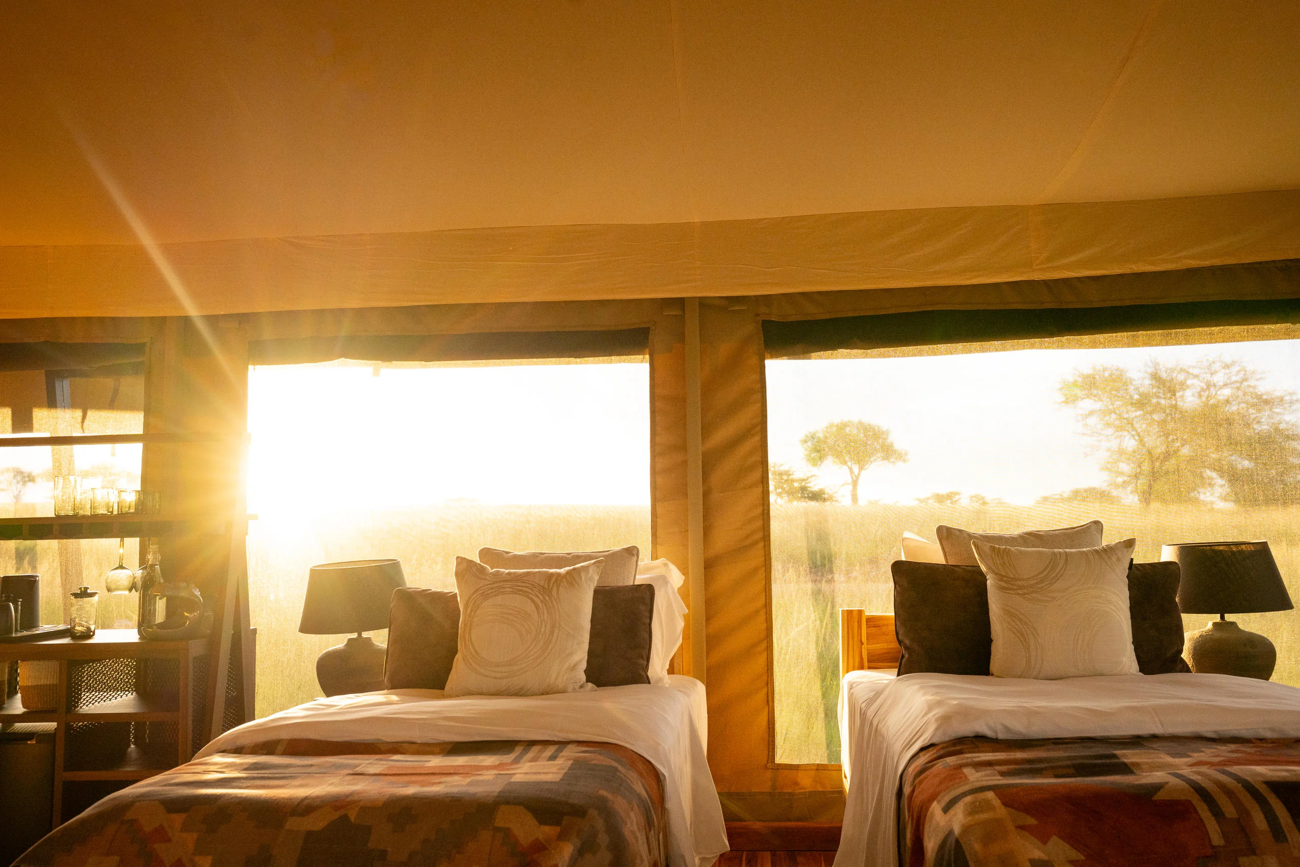 A tent bedroom with twin beds at sunrise