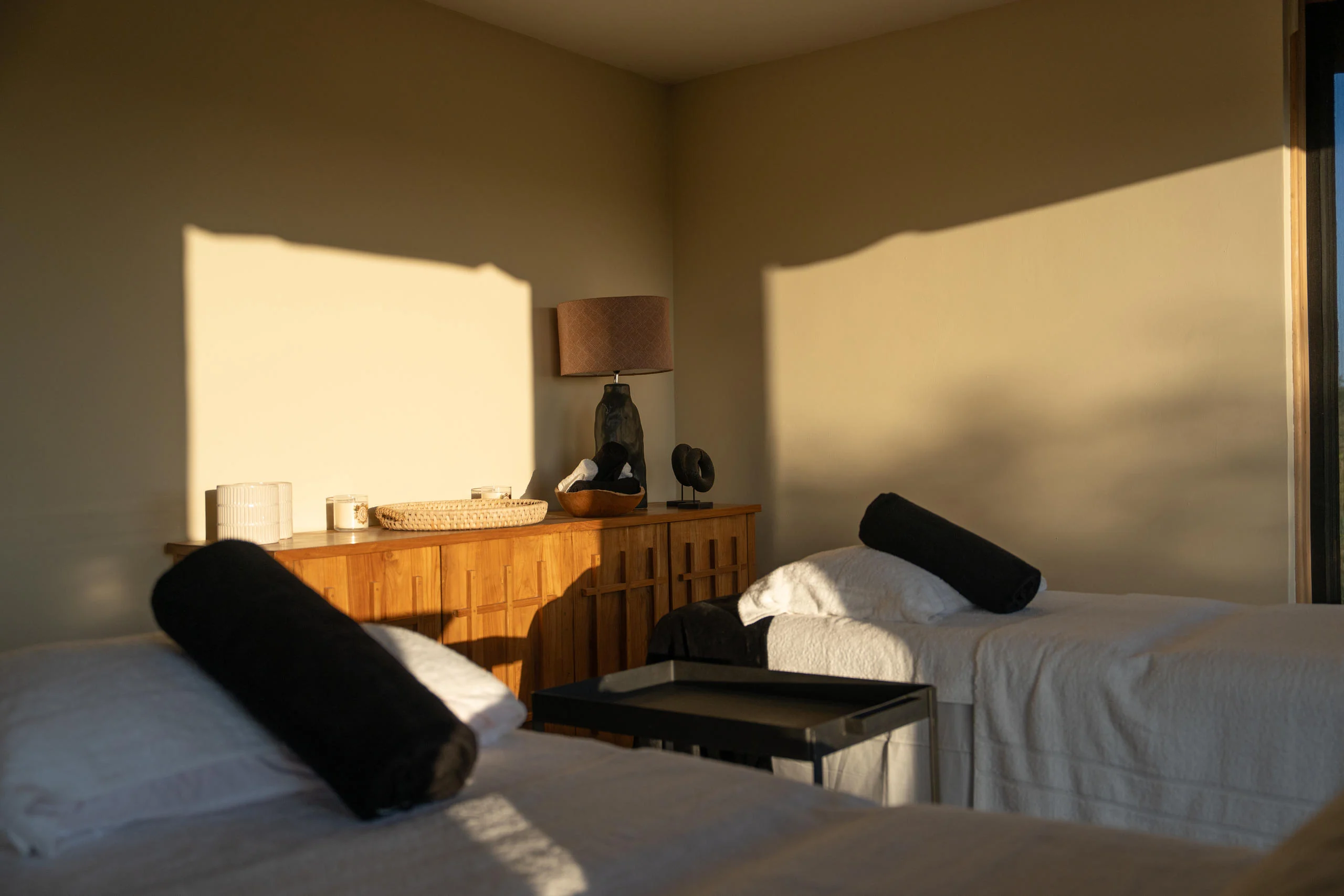 A bedroom with a timber bed and a window onto the plains