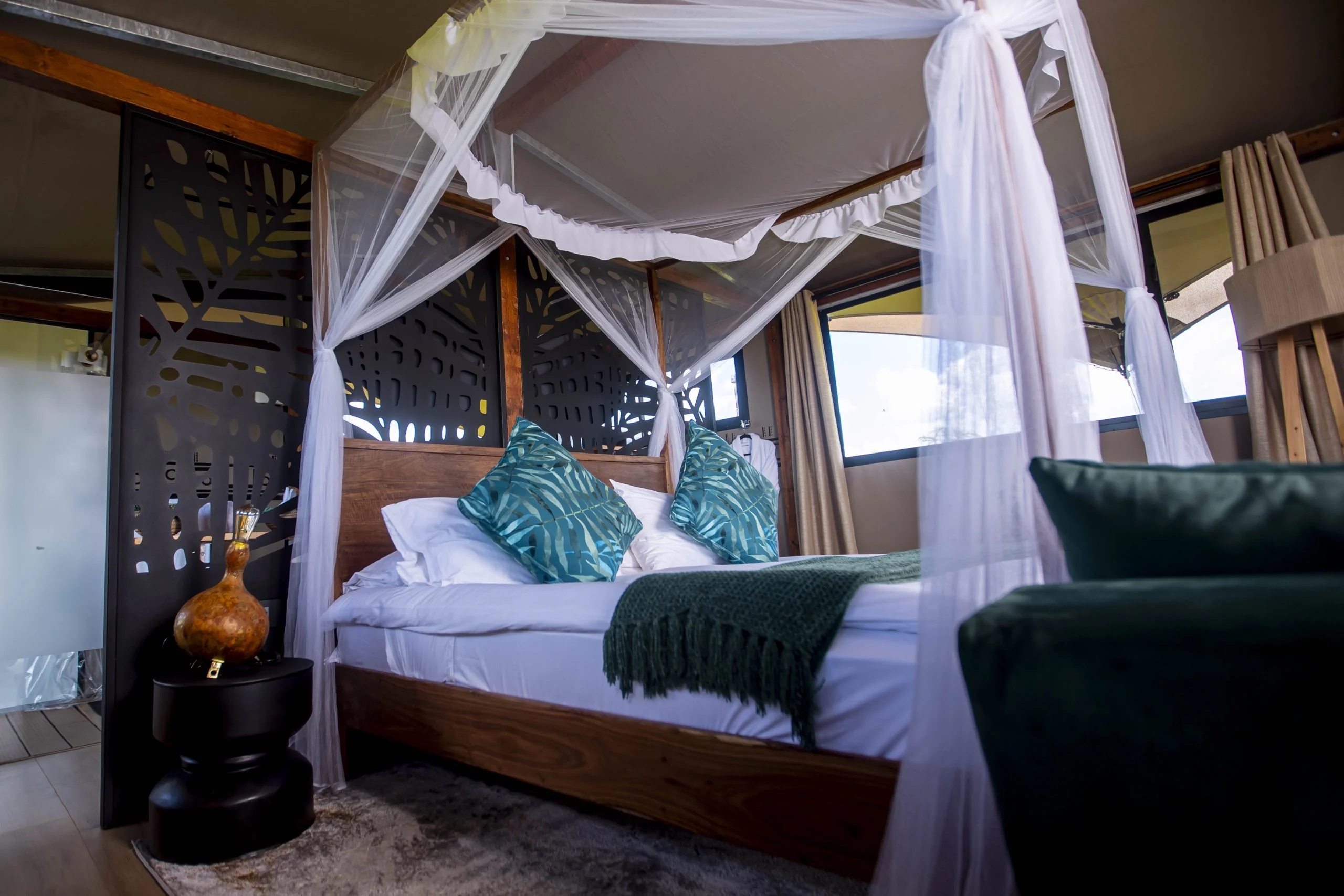 A bedroom with a canopied bed and green cushions
