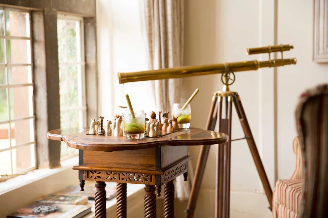 A drinks table with a brass telescope beside a window in the drawing room