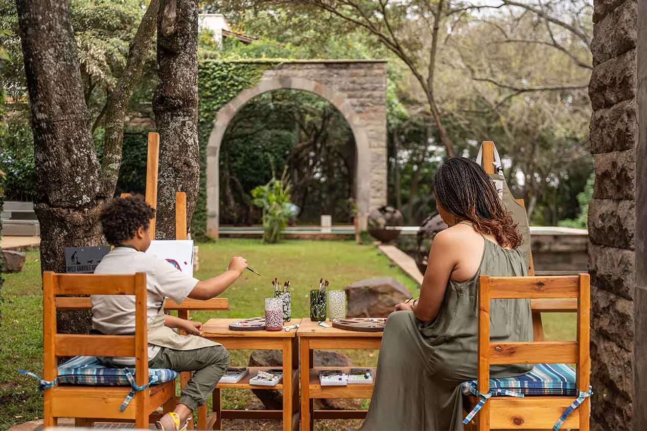 An adult and a child painting at easels in the garden