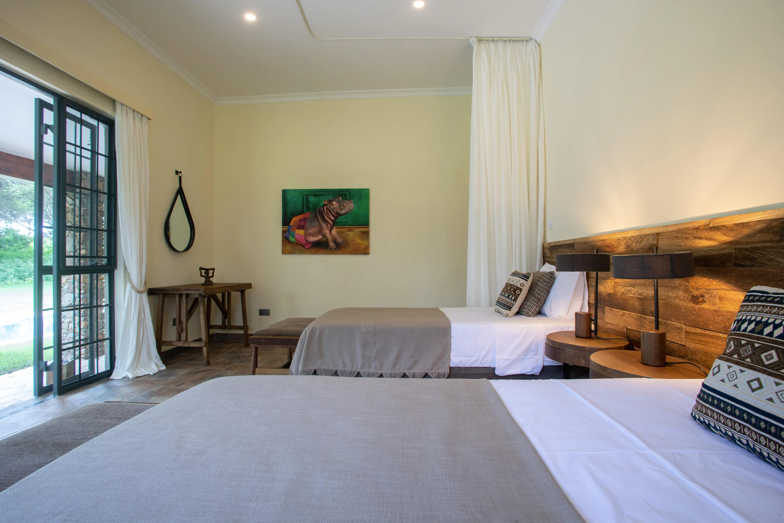 A bedroom with twin beds and a painting above the headboard