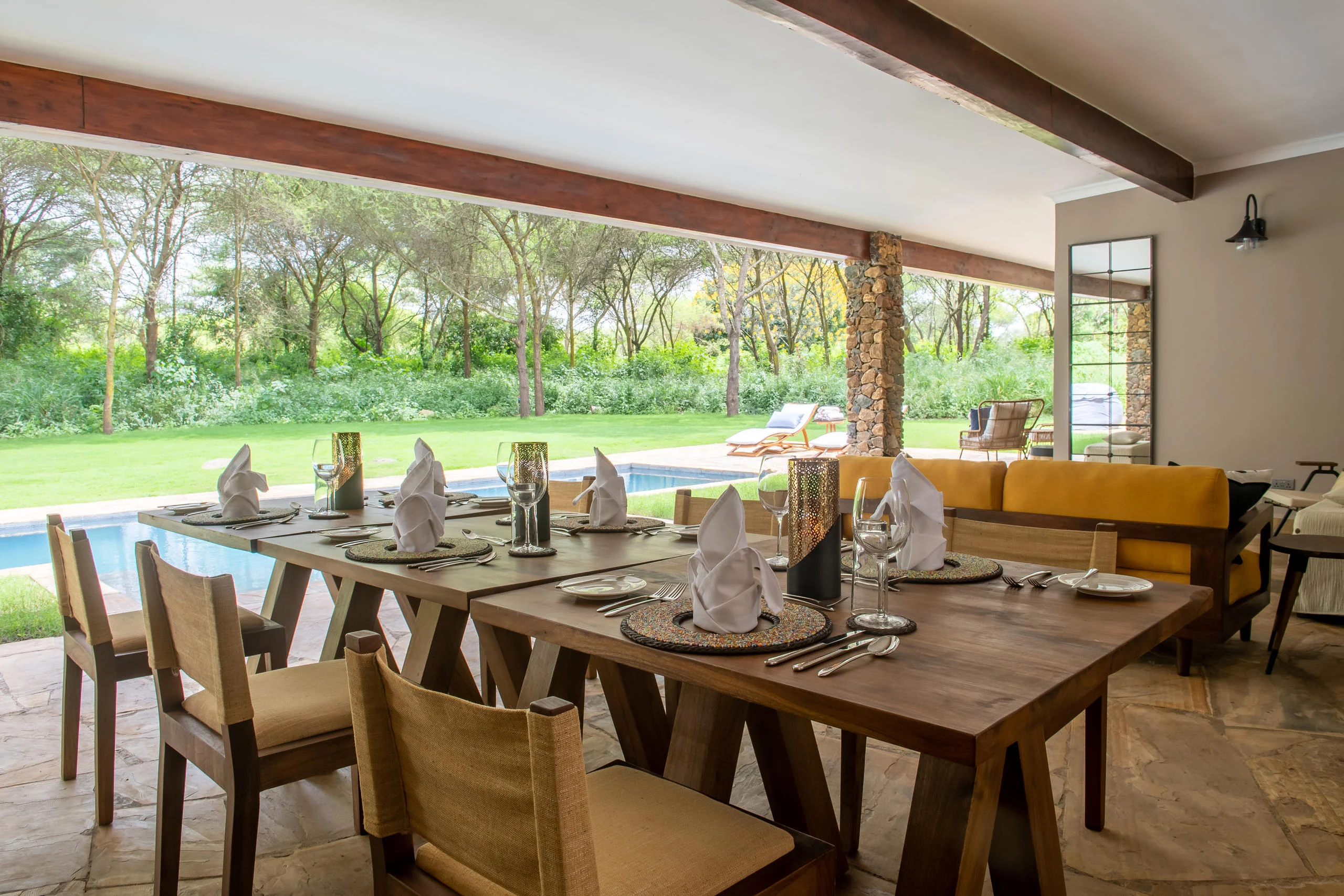 The dining table set on the veranda, looking out to the garden and pool