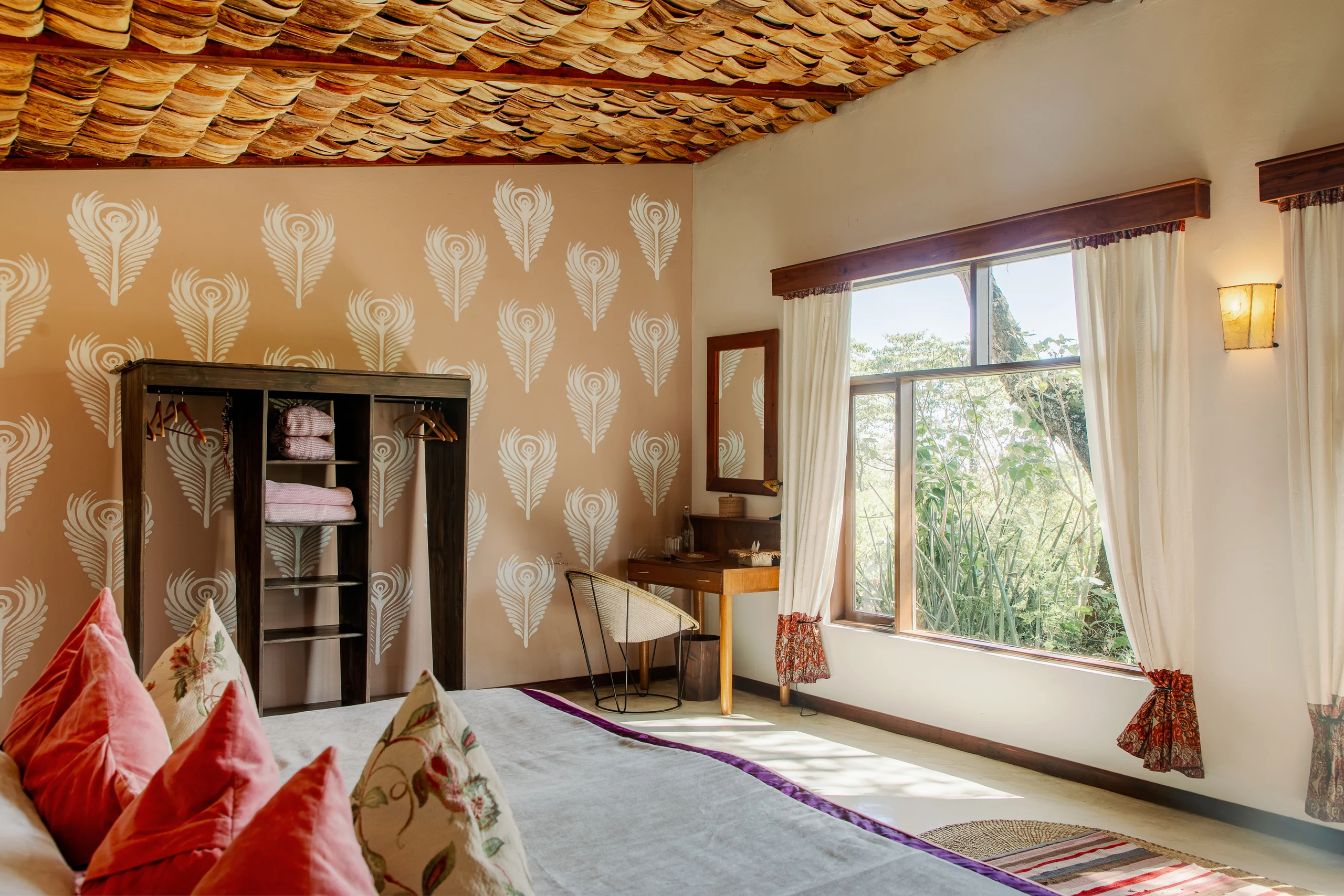 A bedroom with patterned walls and a window onto the garden