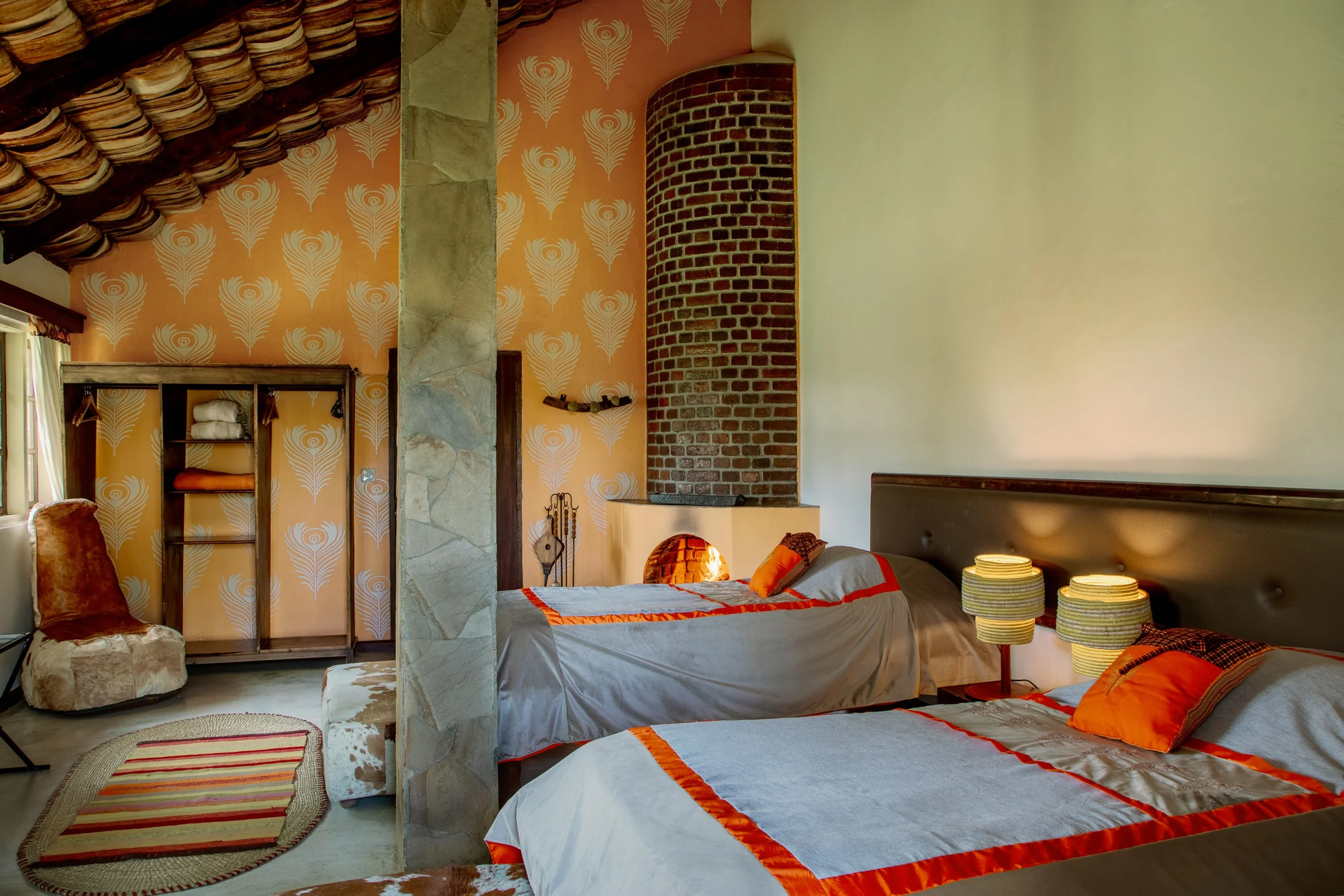 A bedroom with a brick fireplace column and twin beds