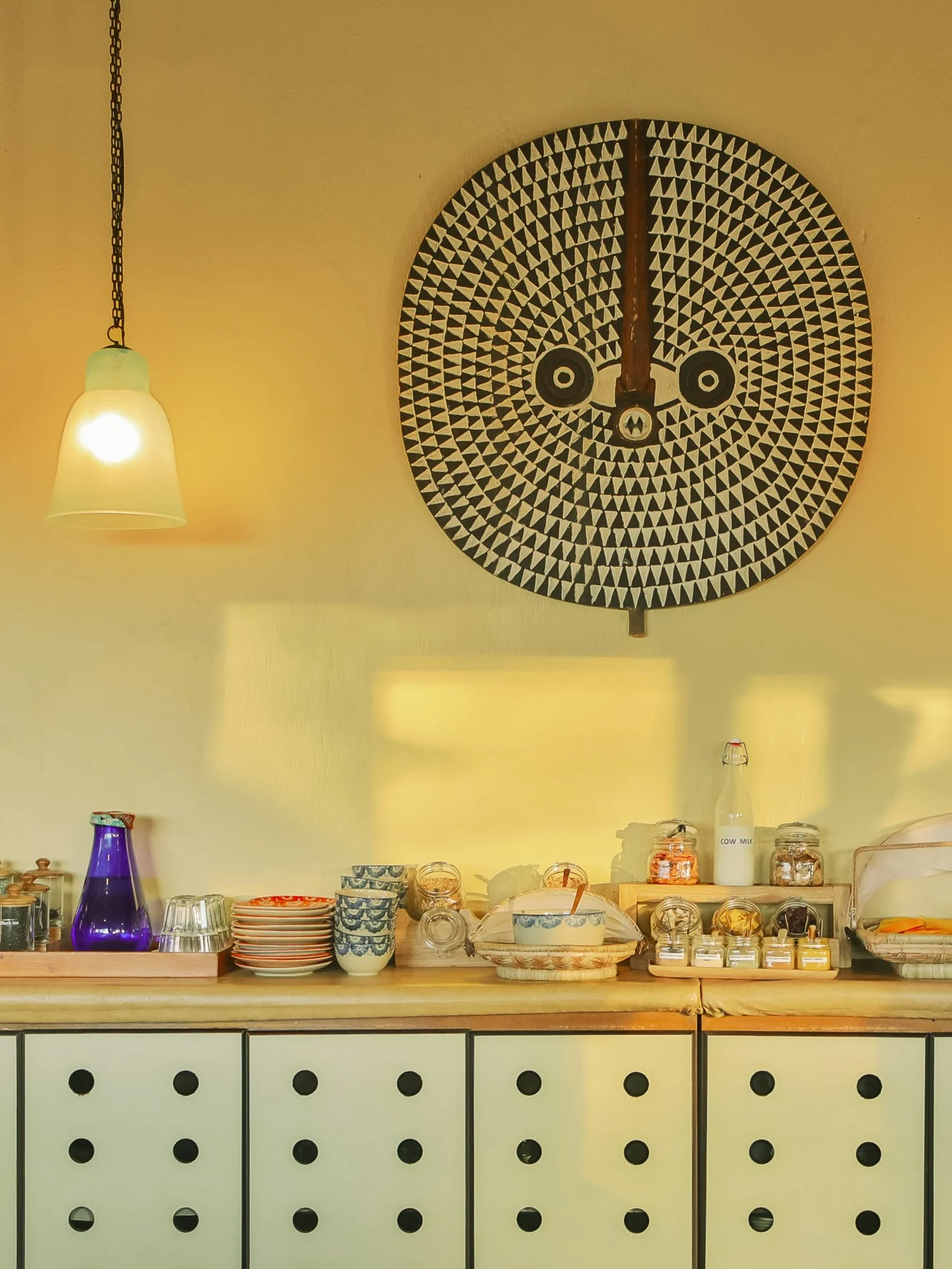 The kitchen dresser with crockery and a decorative mask