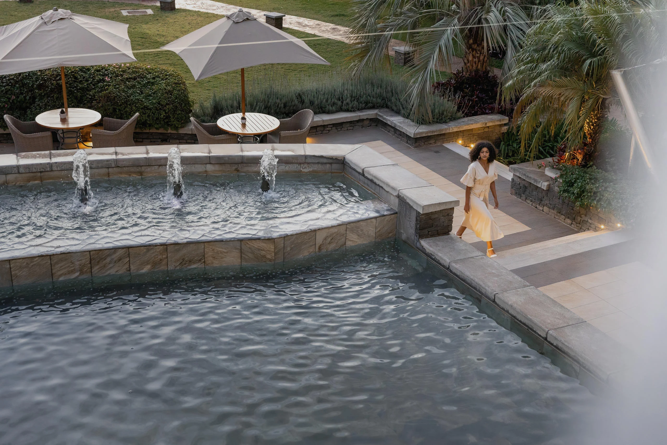 A guest beside the fountain pool with parasols beyond