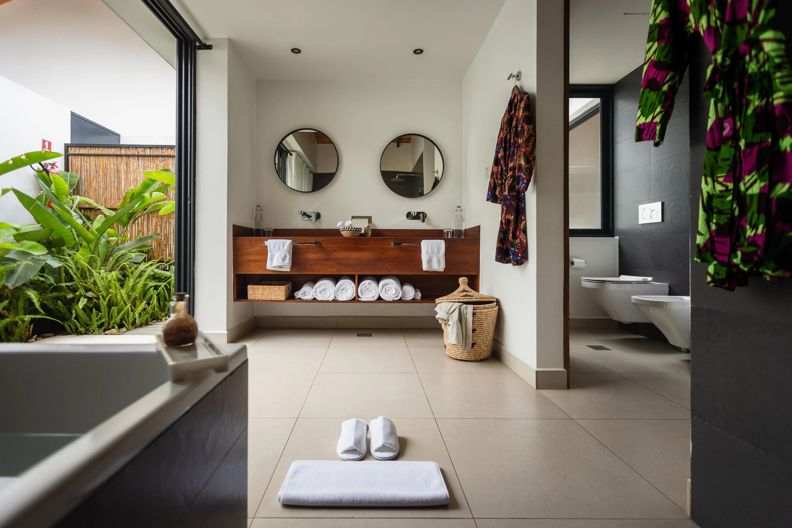 A bathroom with twin basins and a plant-filled courtyard