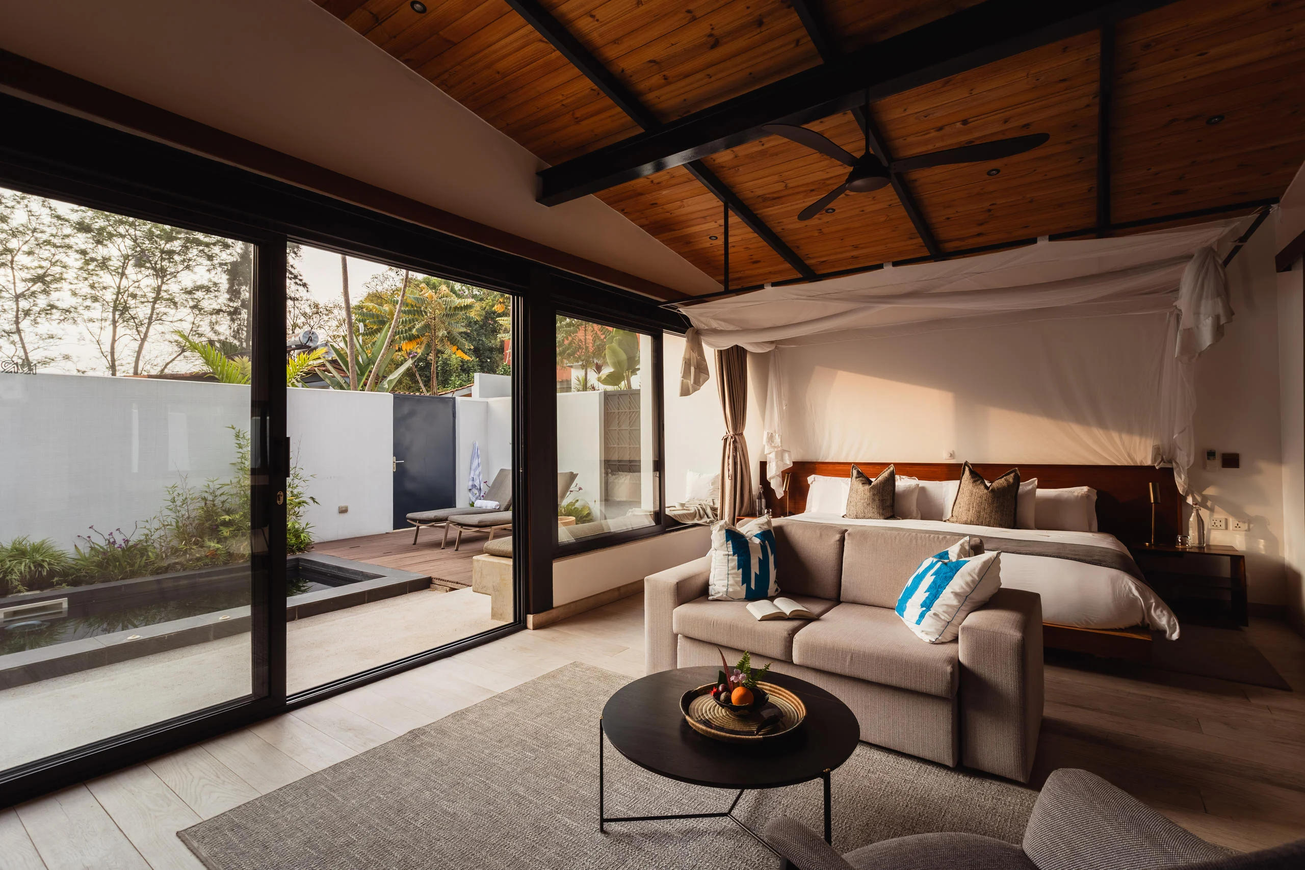 A villa bedroom with a canopied bed and glass walls