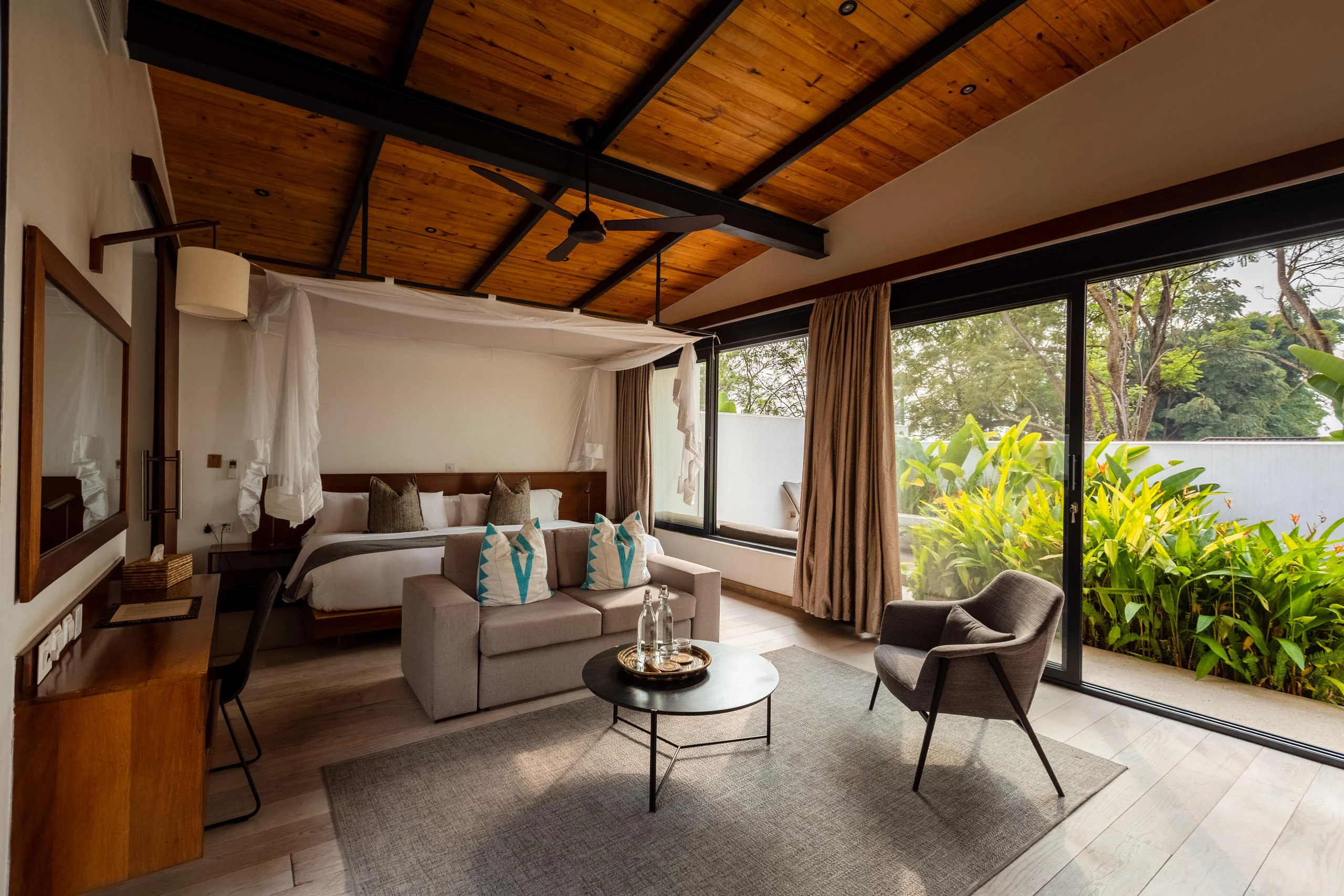 A villa with its sitting area and bed under a timber ceiling