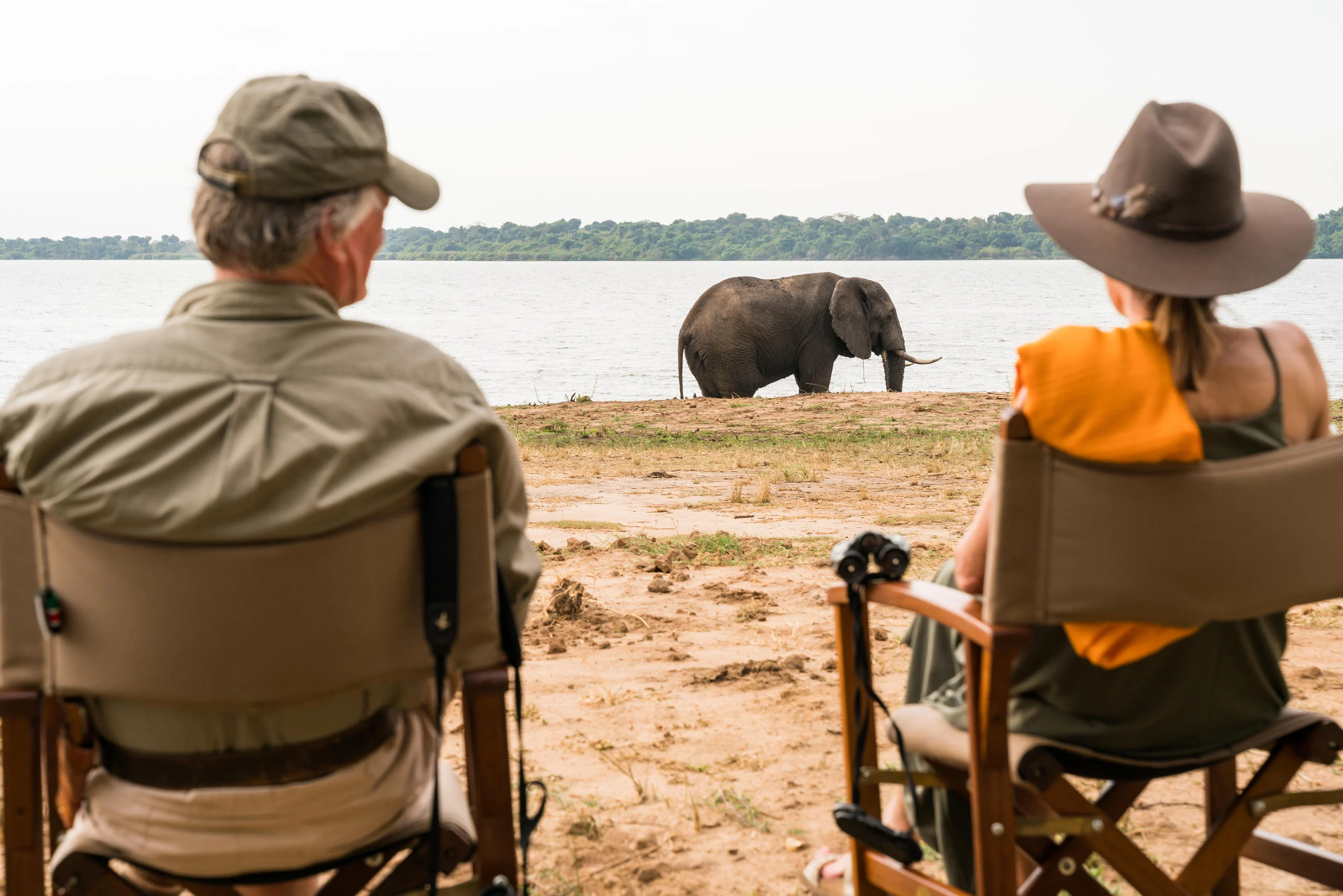 Two guests watching an elephant on the lakeshore