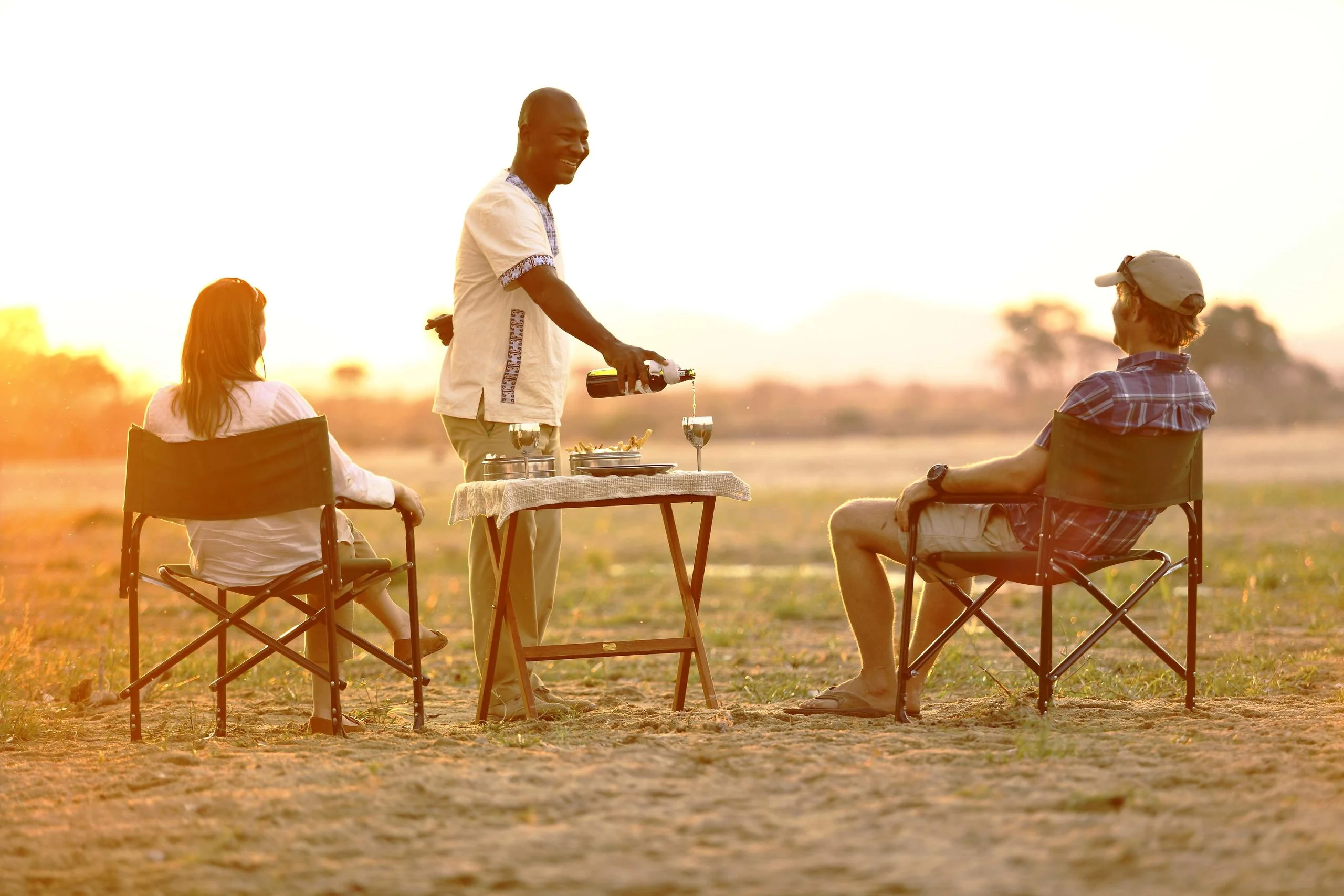 Drinks being poured for guests on the plains at sunset