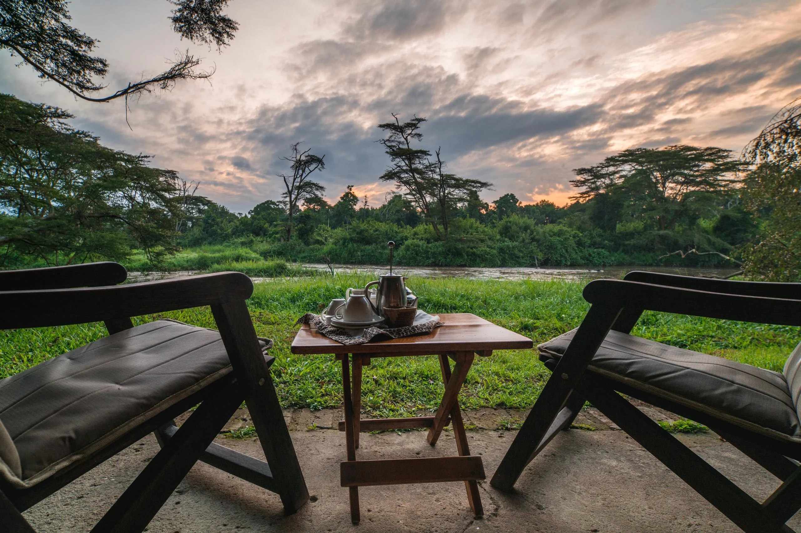 Chairs on a tent deck above the river at dusk