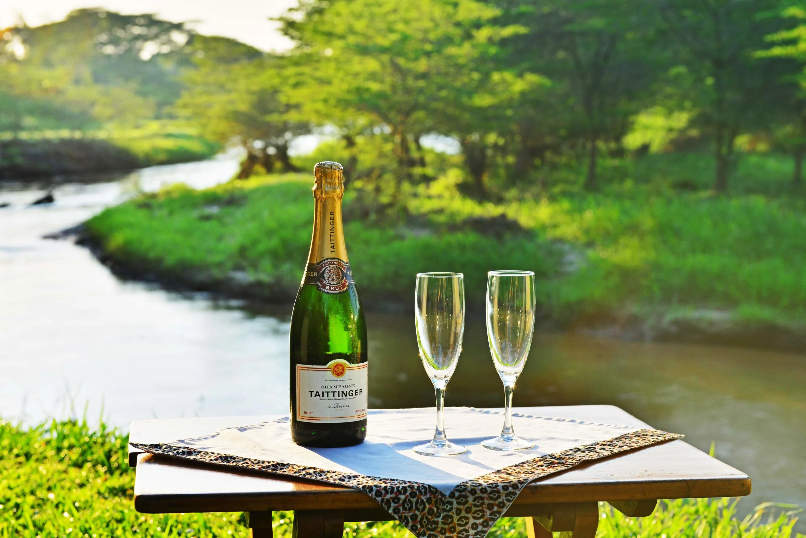 A bottle and two glasses beside the river