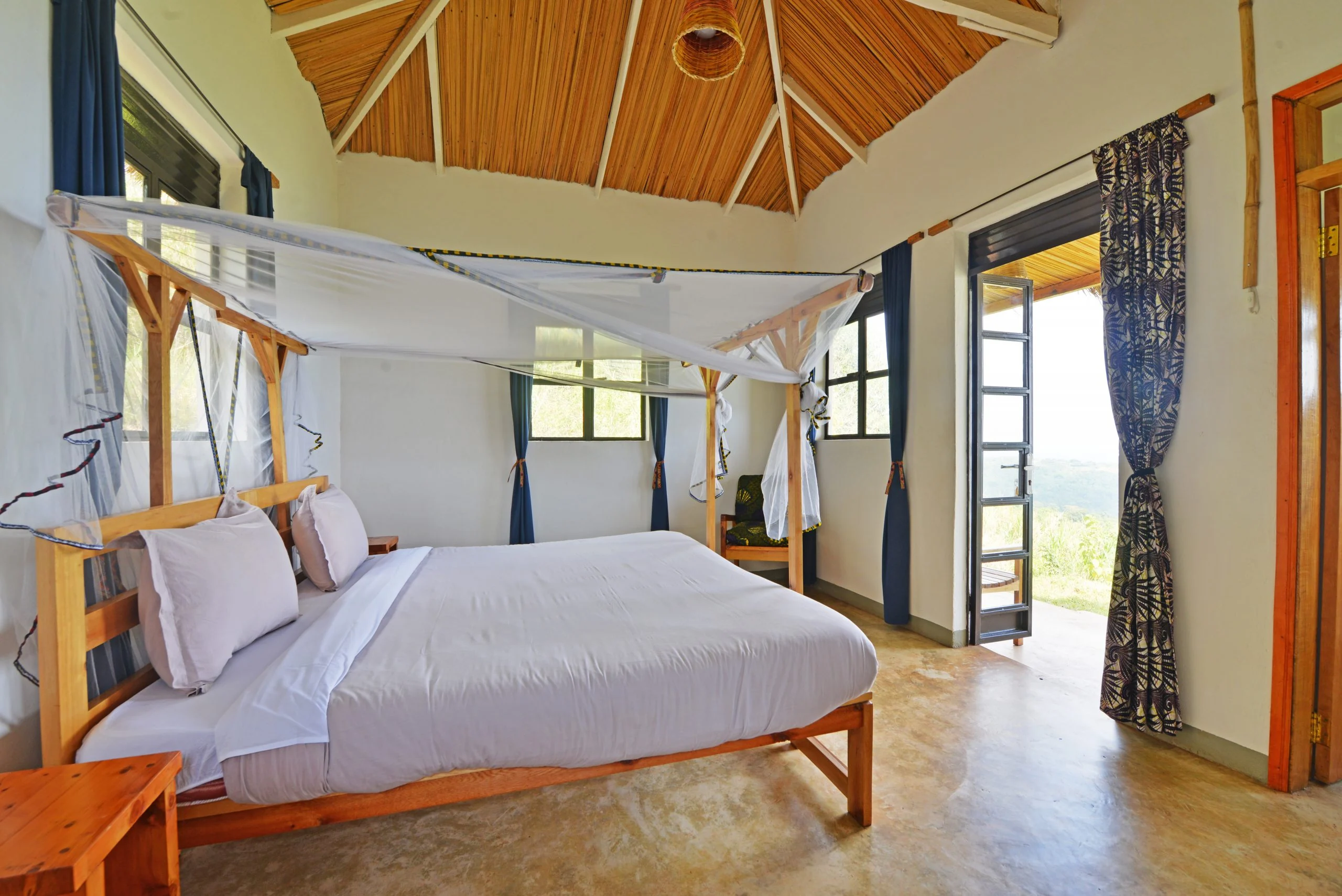 A bedroom with a canopied bed and doors onto the veranda