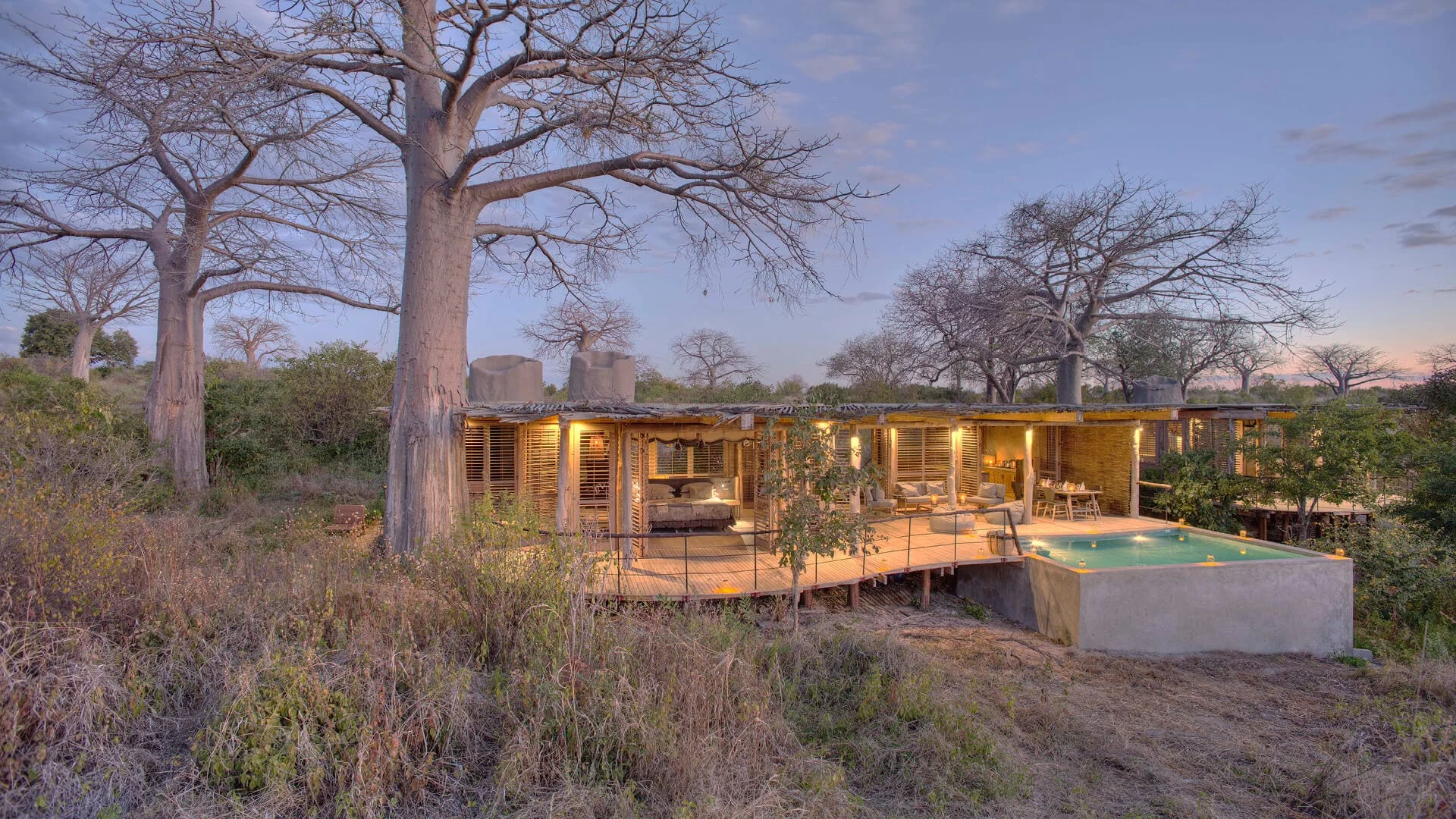 The house among baobabs at dusk, with its pool below
