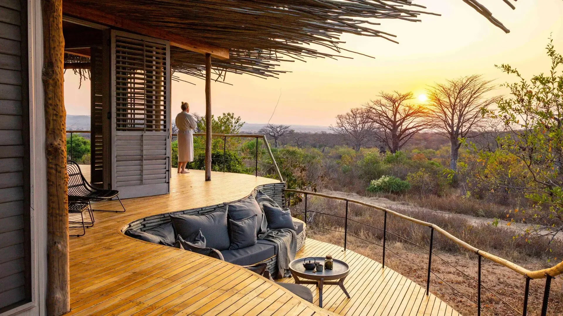 A deck with a sofa looking over the woodland at sunset