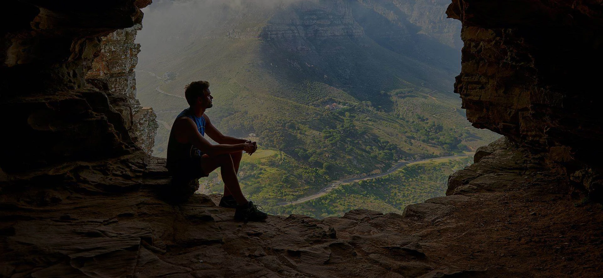 A guest sitting at the mouth of a cave above the valley