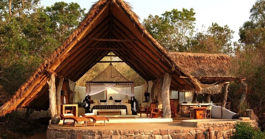 A thatched guest banda open at the front, lit at dusk