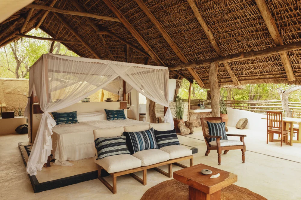 A four-poster bed under thatch with the river beyond