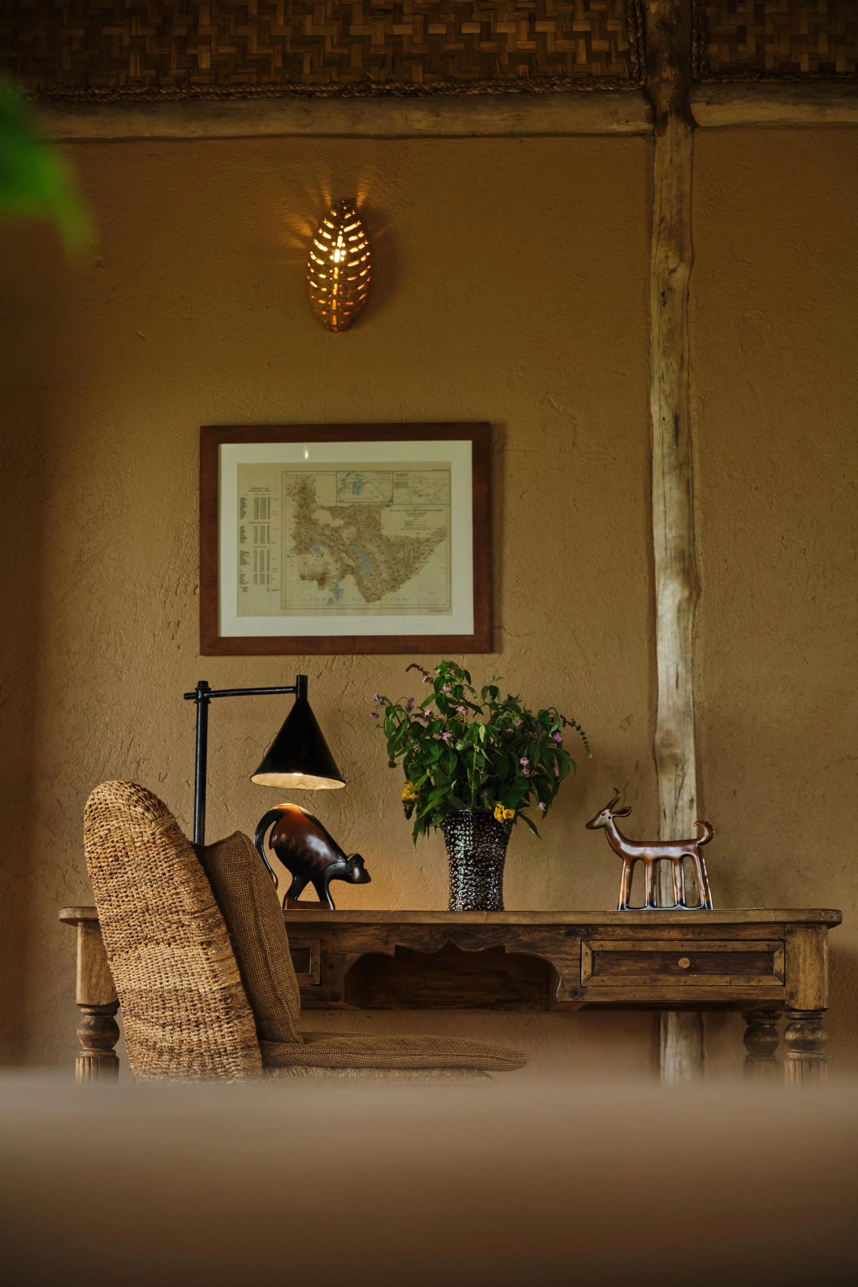 A corner of a cottage with a framed map and a lamp