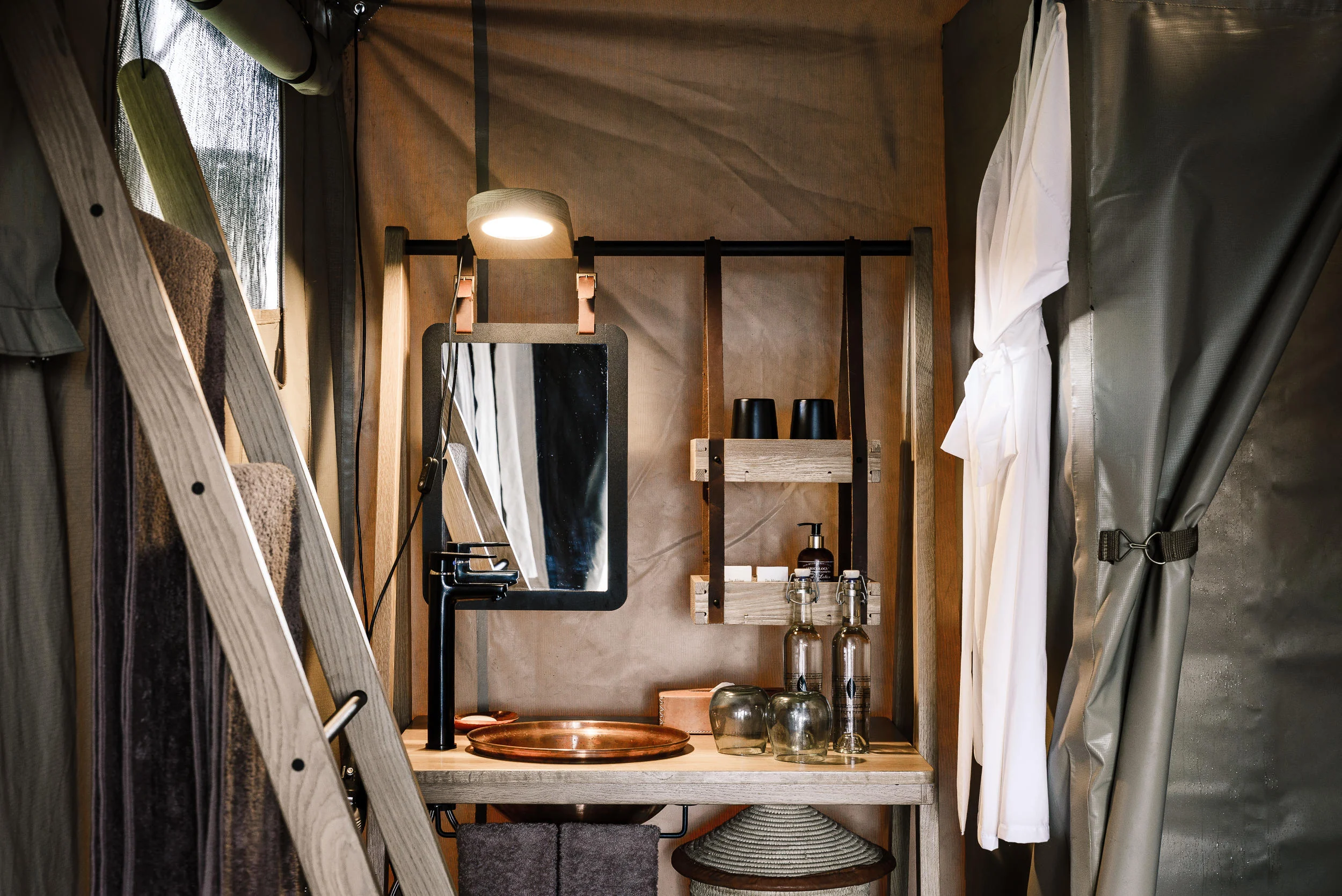 A tent bathroom with a basin and mirror