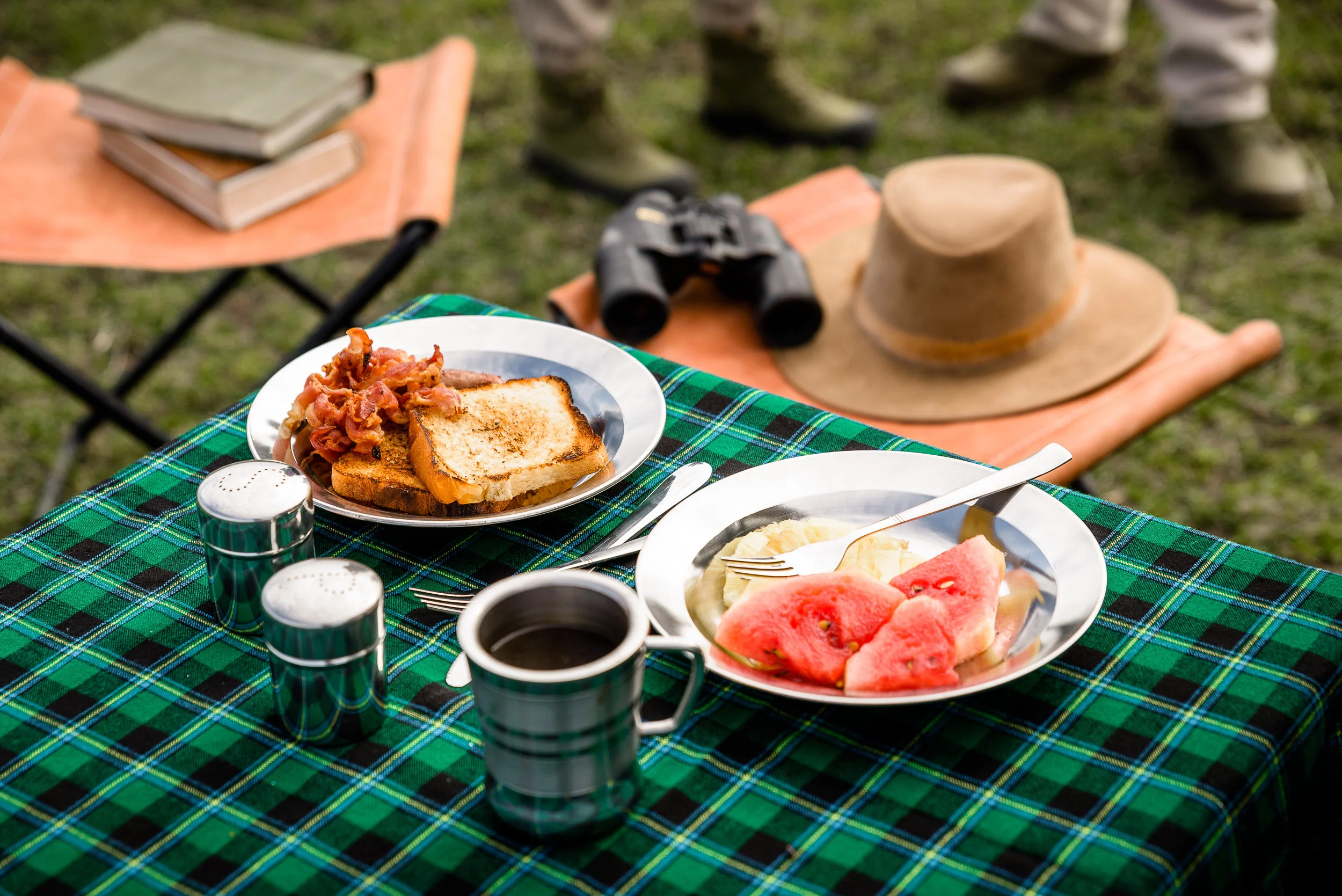 Breakfast on a tartan cloth with binoculars and a hat