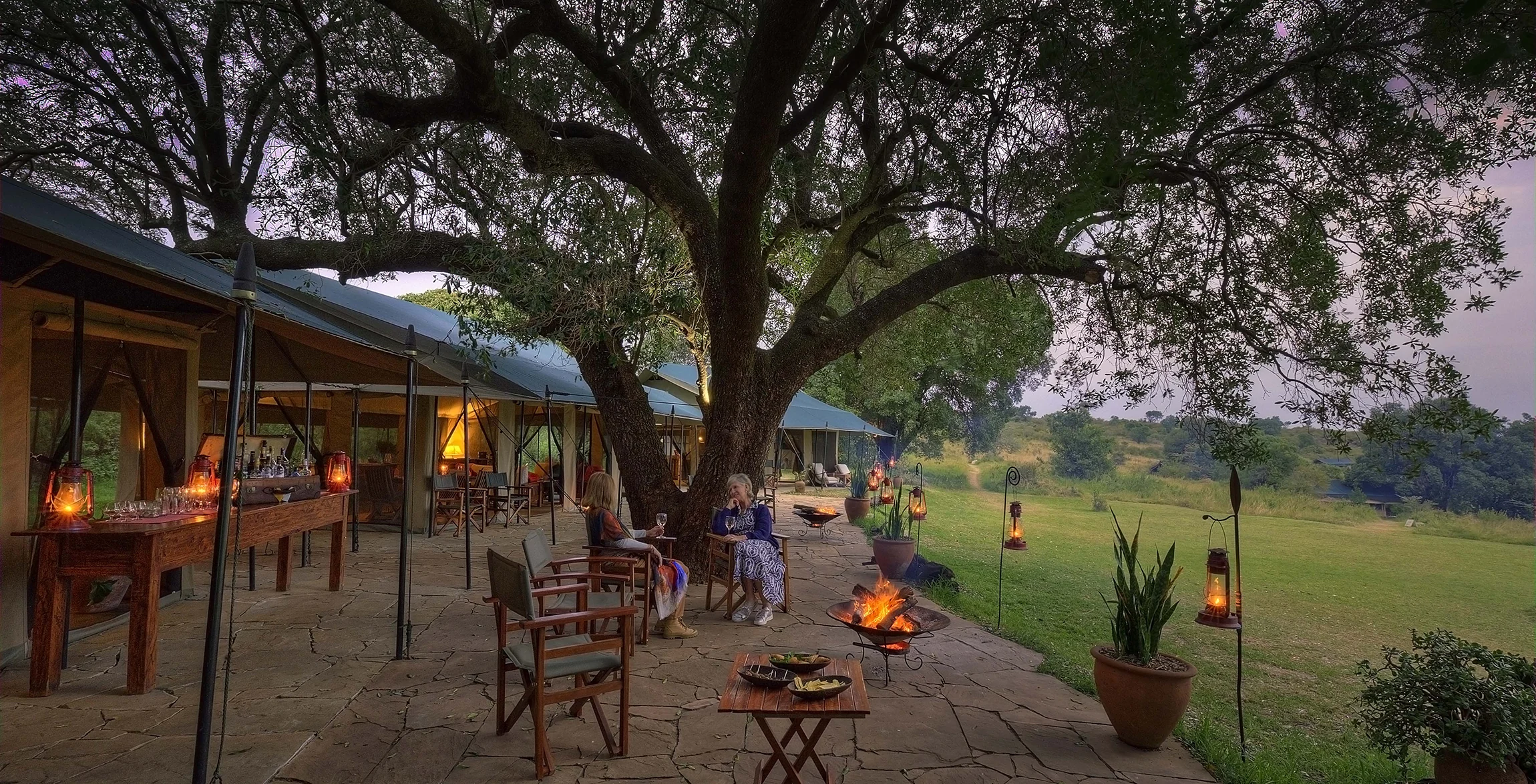 The lounge tent under a tree, with a fire
