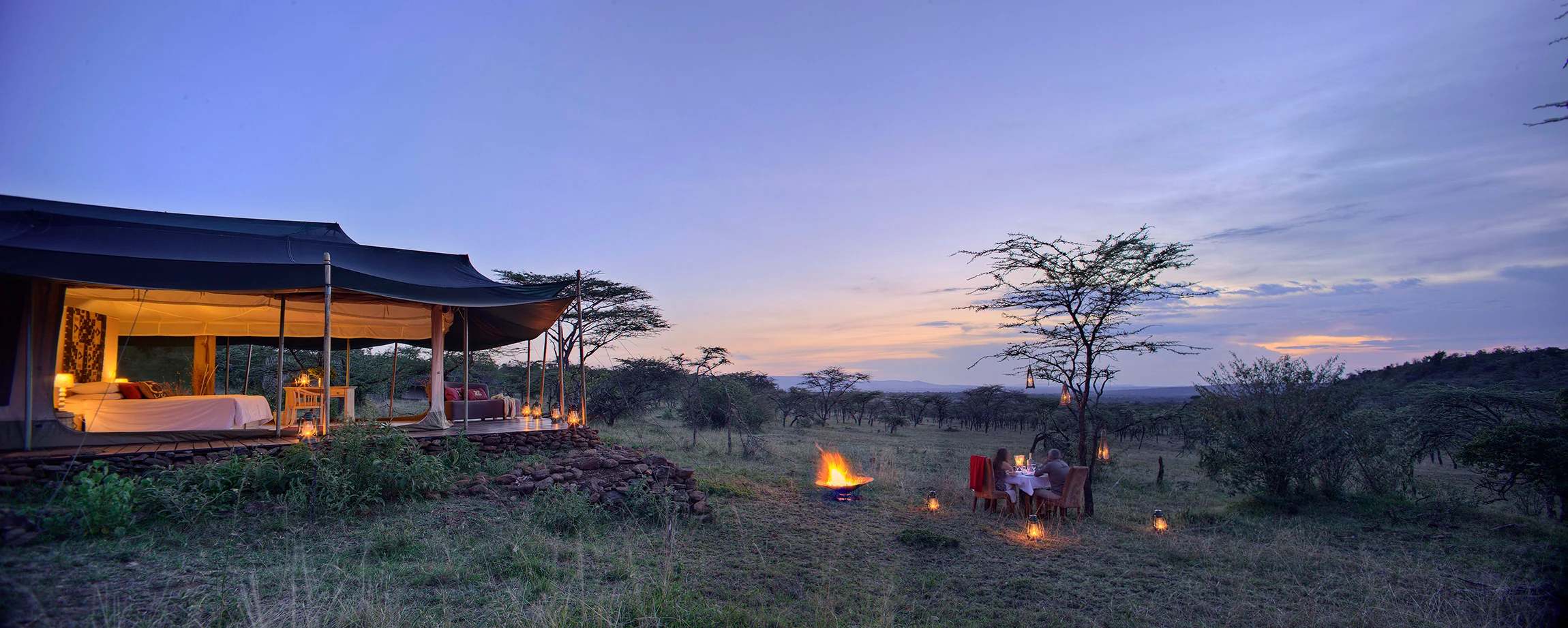A private dinner set beside the camp at dusk