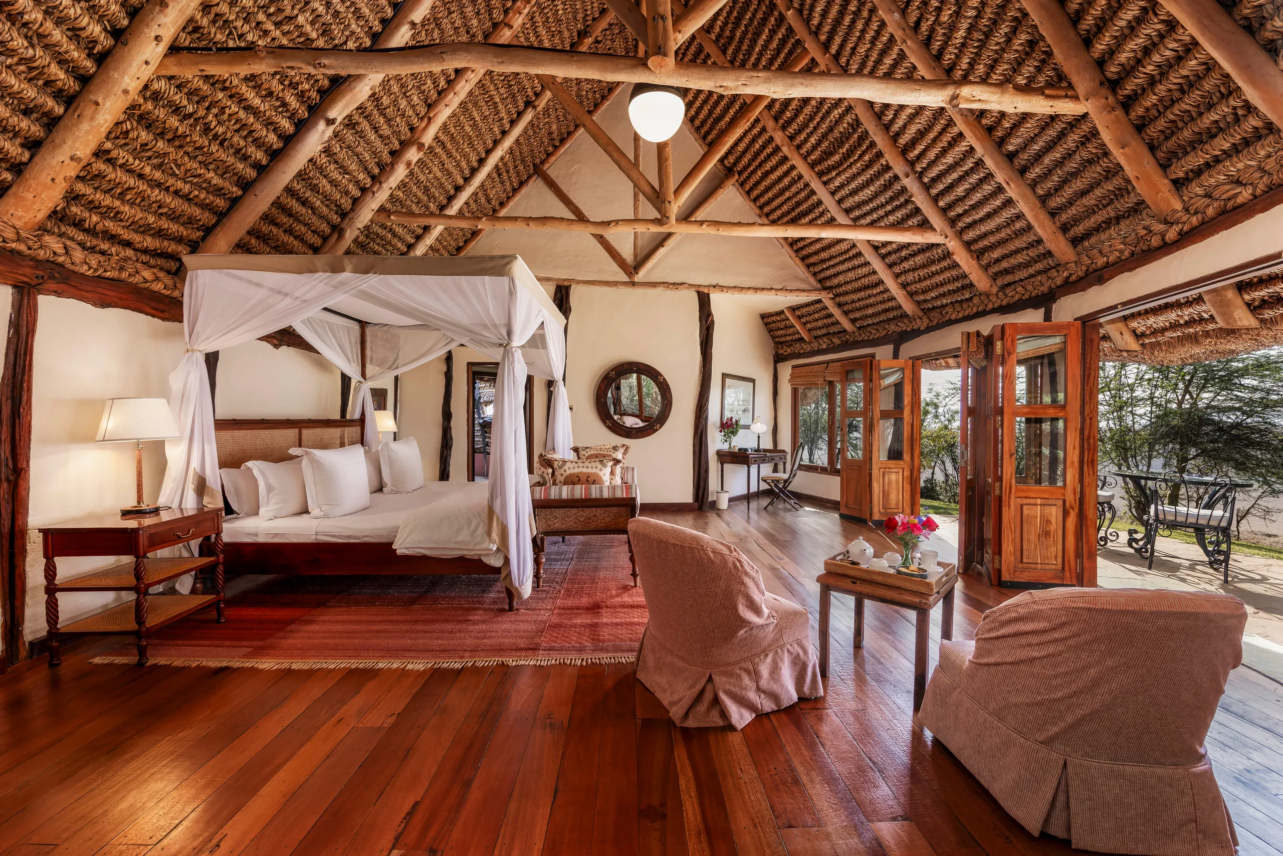 A four-poster bed and sitting area inside a cottage at Kifaru House Lewa