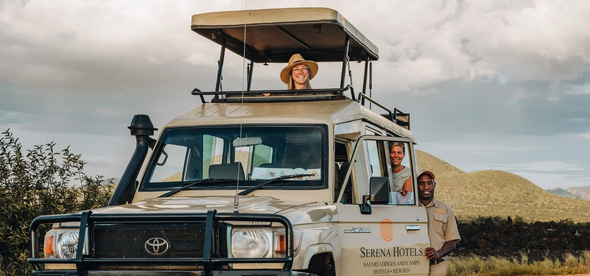 Guests and a guide in an open-roofed safari vehicle