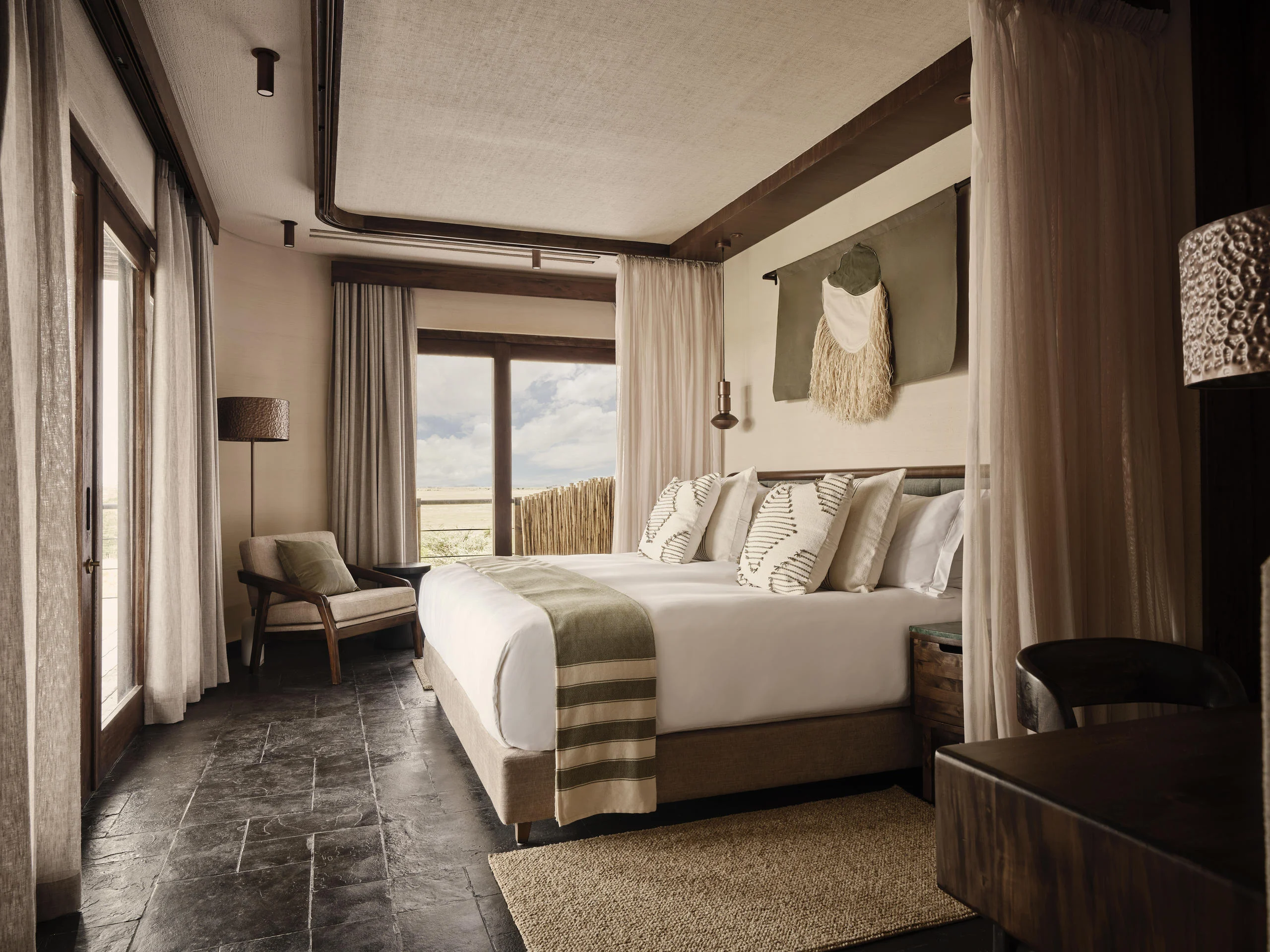A bedroom with a striped throw and doors onto the plains