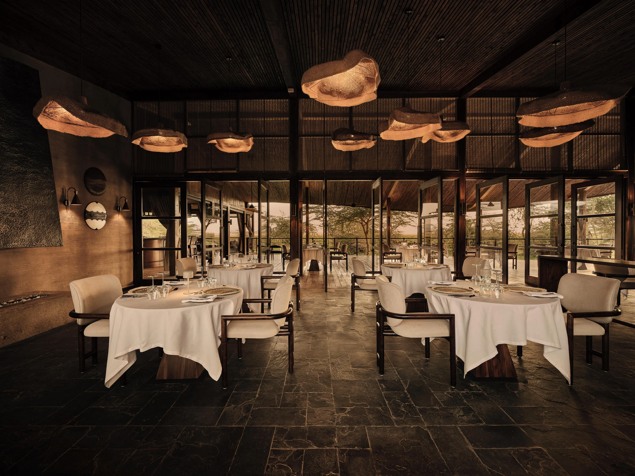 The dining room with tables laid and woven pendant lamps