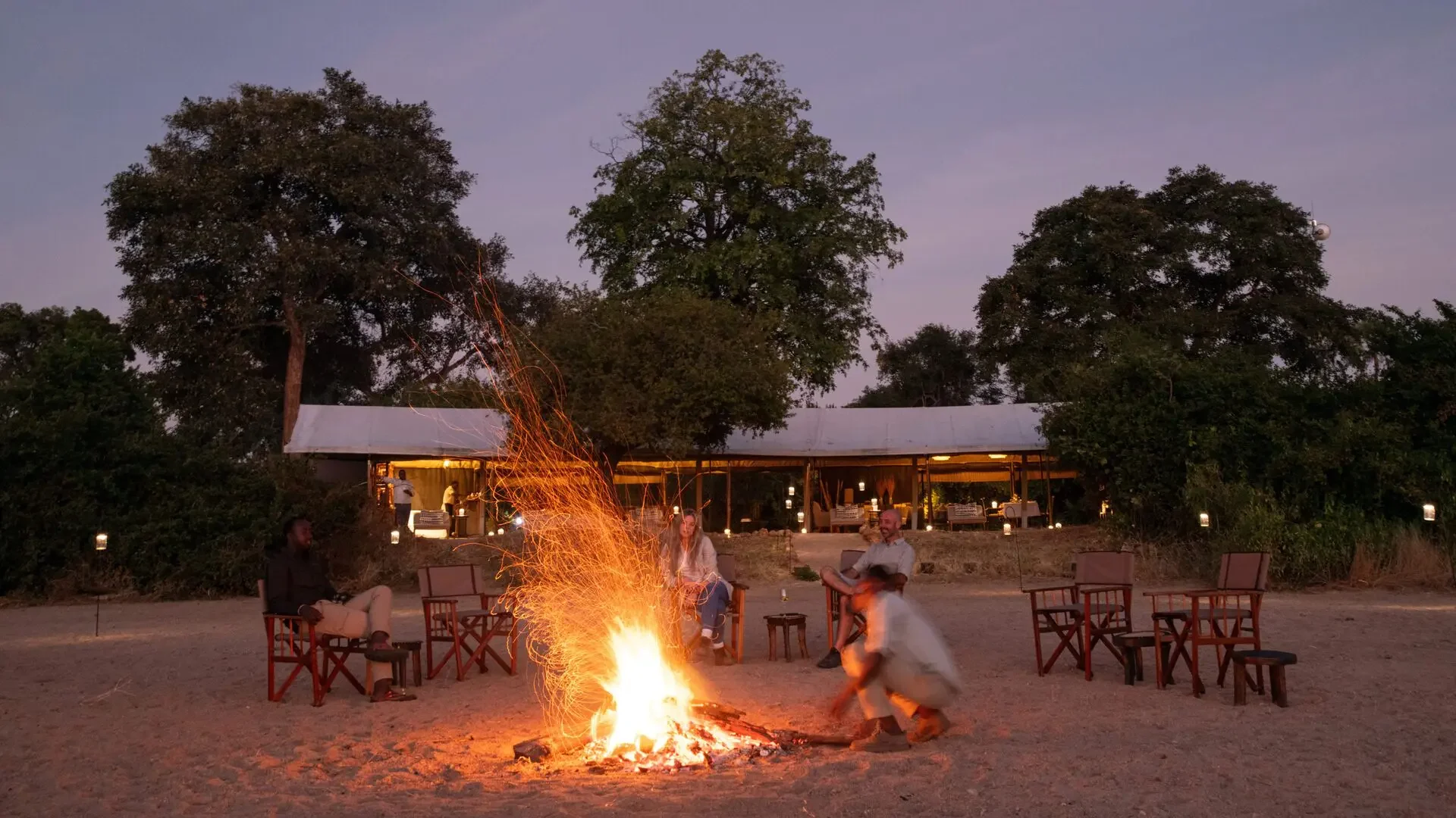 Guests around a campfire in front of the main tent