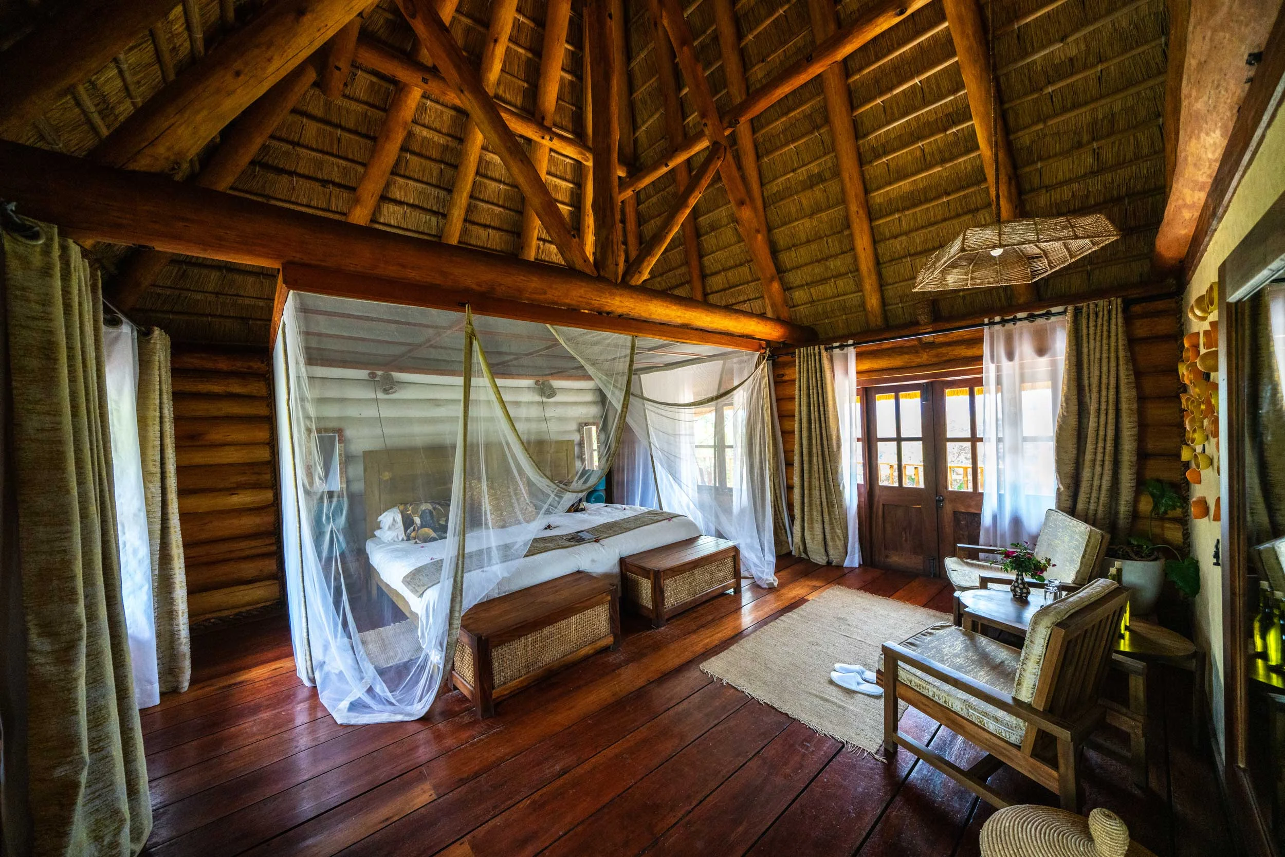 A cottage bedroom with a draped bed and timber walls